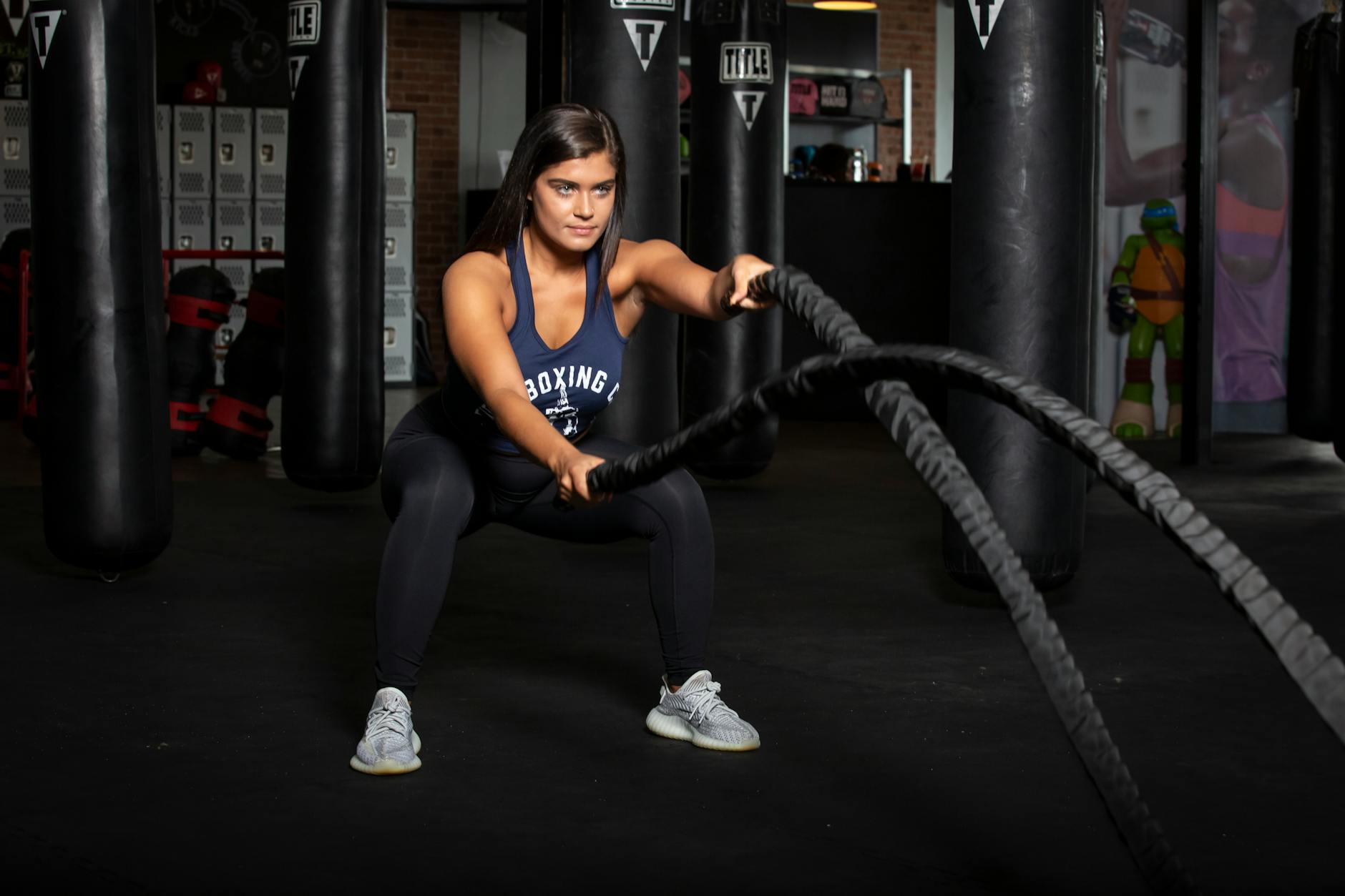 Female athlete working out with battle ropes in a modern gym setting. - fat burning workouts