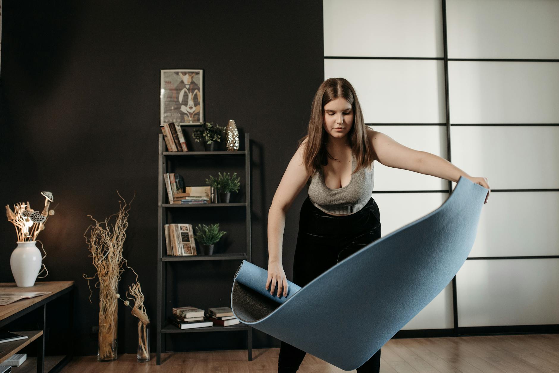 A woman sets up a fitness mat indoors, ready for her home exercise routine, promoting a healthy lifestyle. - gym workout for beginners