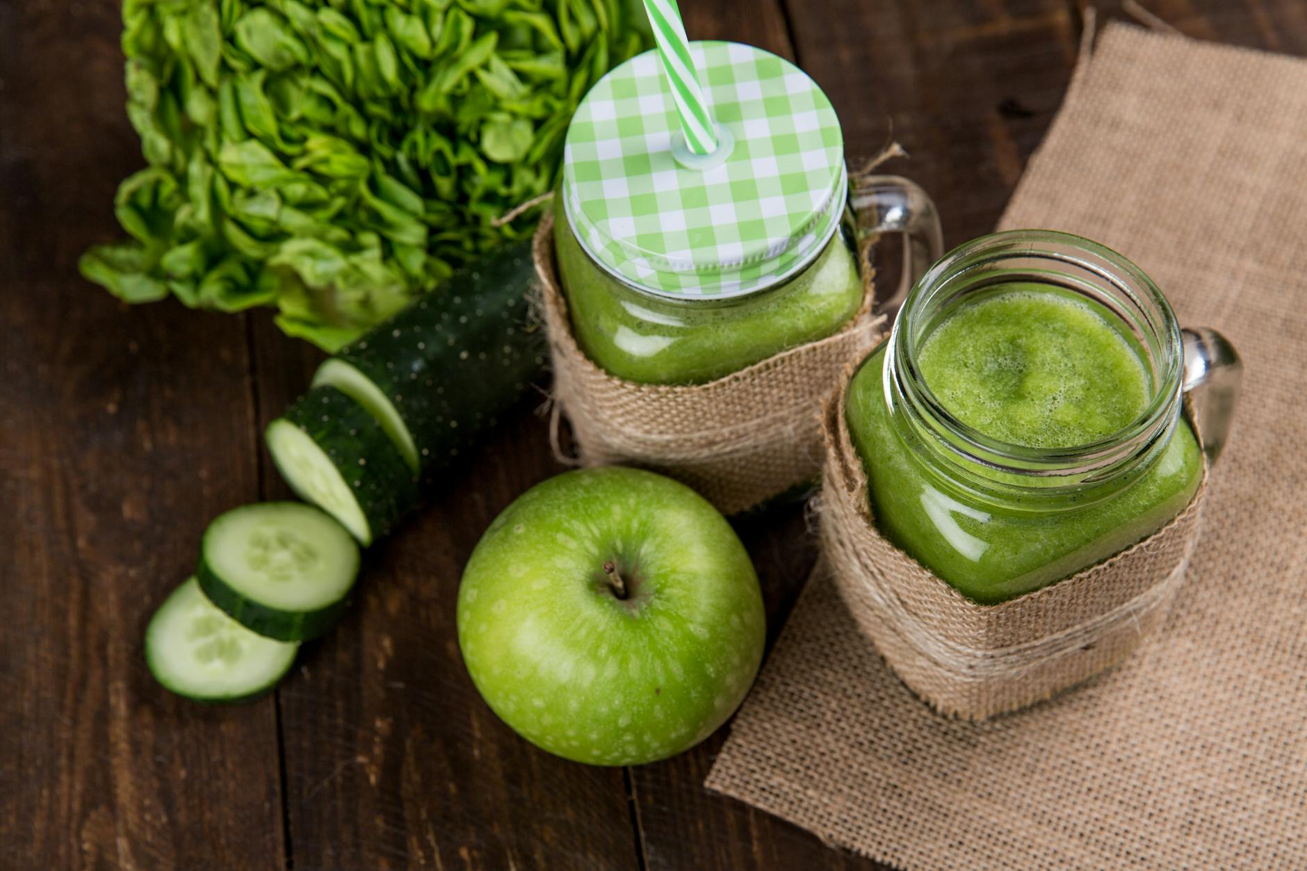 Refreshing green smoothie made with apple, cucumber, and lettuce served in mason jars on wooden background. - healthy green smoothie
