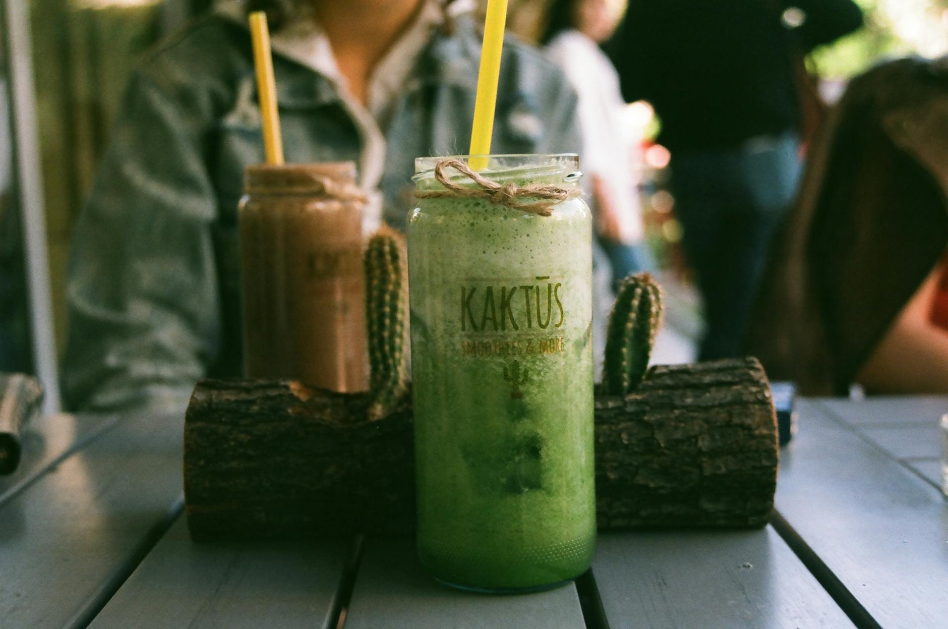 Close-up of green and brown smoothies on a rustic table with twine and cactus decor, perfect for summer relaxation. - healthy green smoothie
