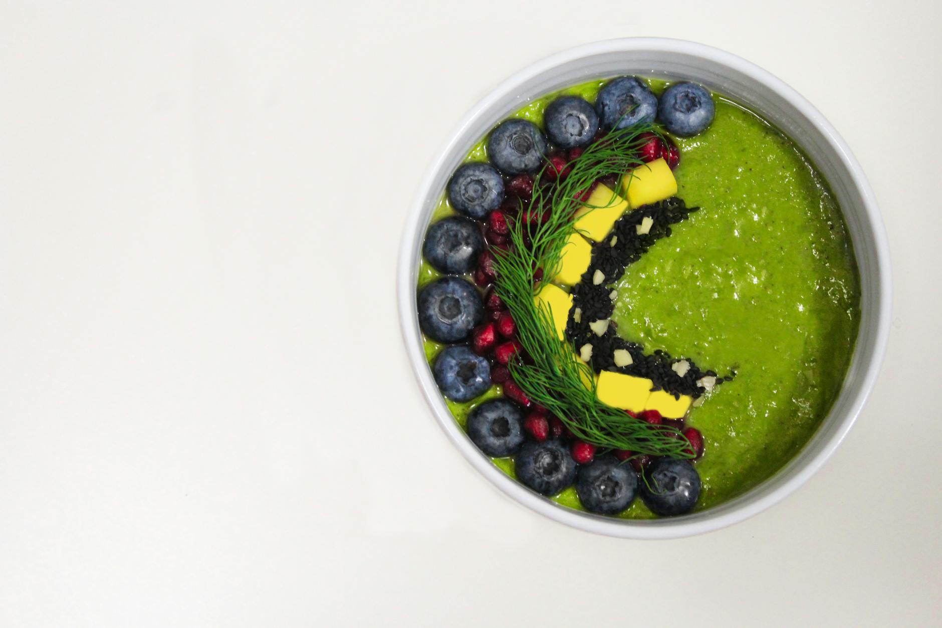 A vibrant green smoothie bowl decorated with blueberries and garnishes for a healthy breakfast. - healthy green smoothie