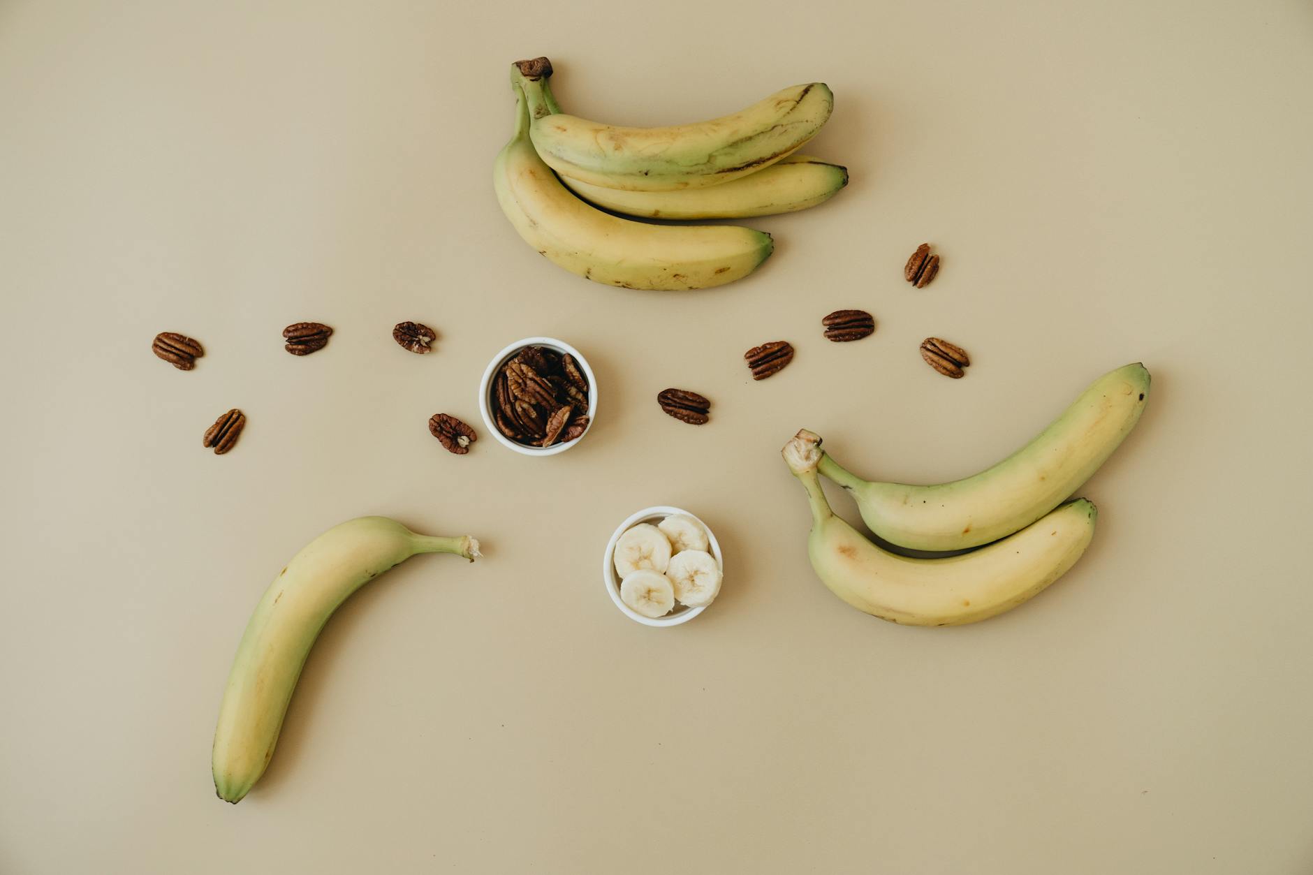 A top view of bananas and pecans artfully arranged on a minimalistic beige background, perfect for healthy eating concepts. - healthy late night snacks