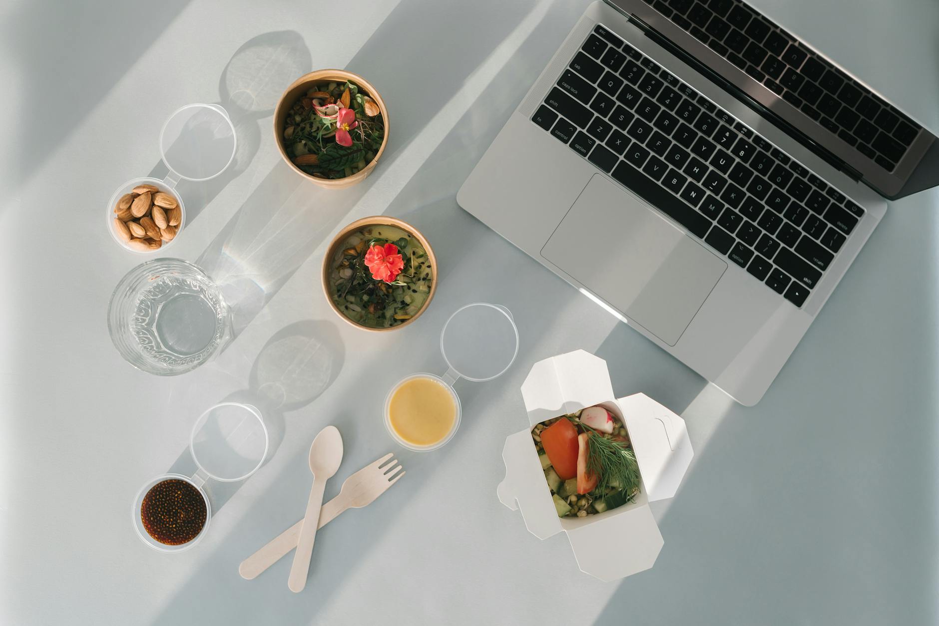 Flat lay of a healthy lunch set with laptop, almonds, and soup bowls, ideal for work-from-home lifestyle. - healthy office snacks