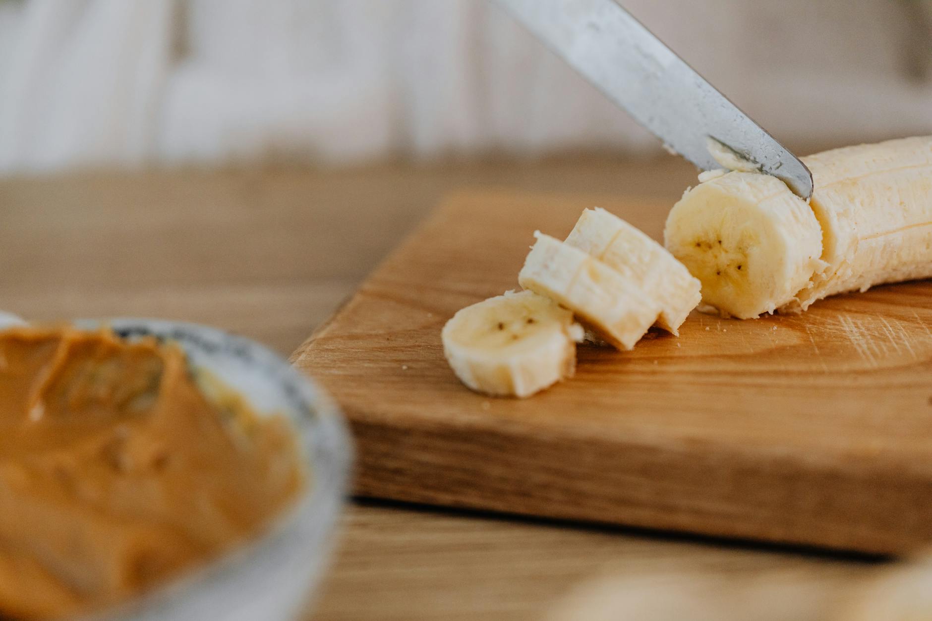 Close-up of a banana being sliced on a wooden board, ideal for healthy snack visuals. - healthy peanut butter snacks