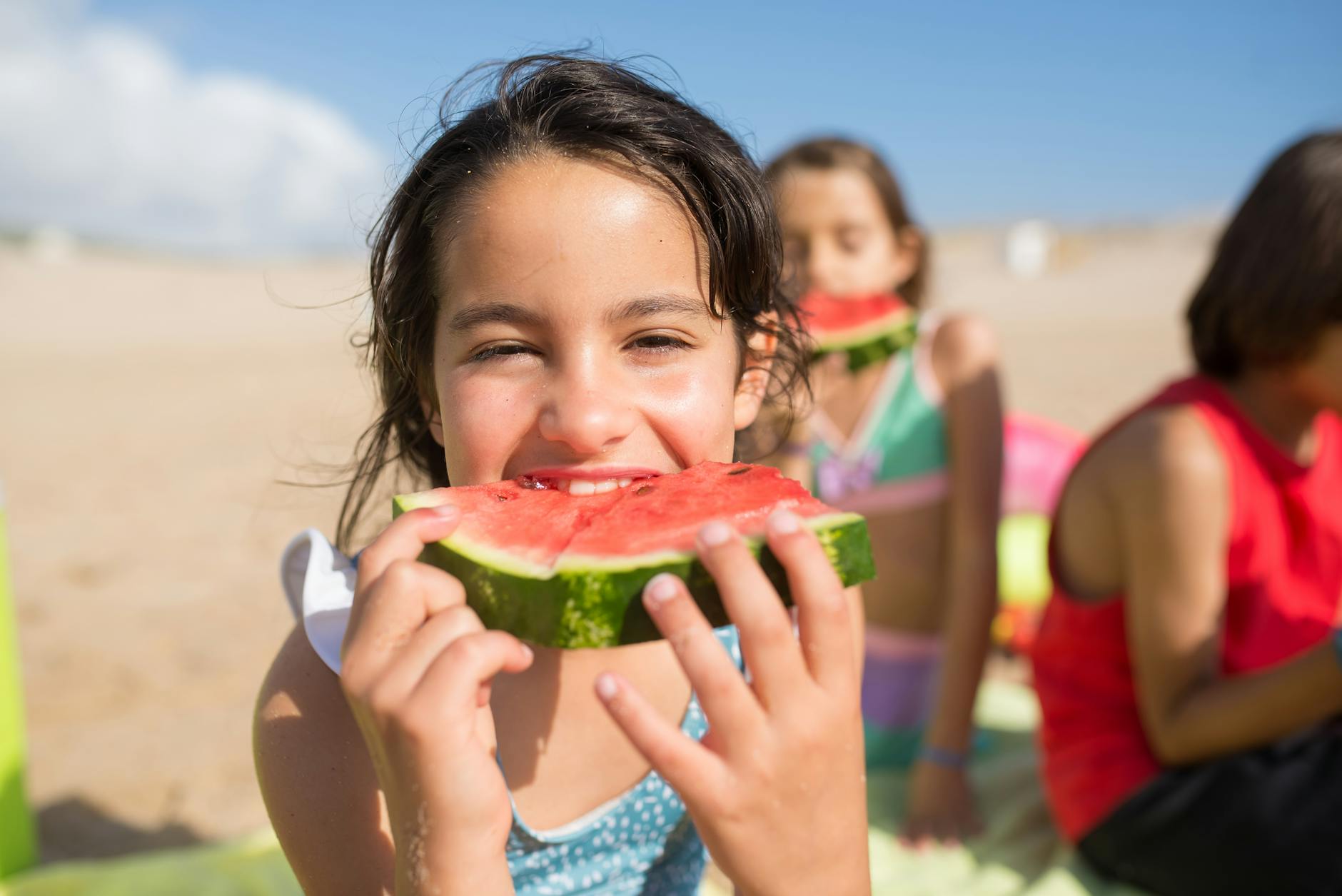 Smiling children enjoying watermelon slices at a sunny beach, capturing summer bliss. - healthy snacks for kids