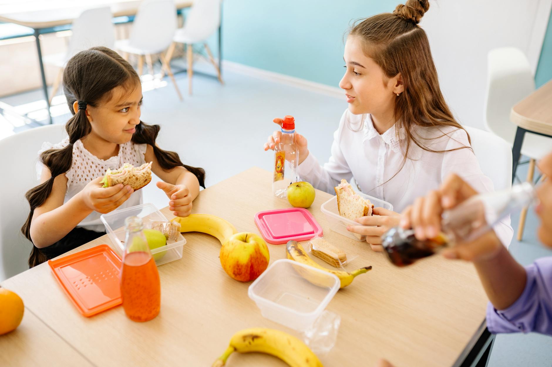 Kids having a fun lunch break with sandwiches, fruits, and drinks in a school setting. - healthy snacks for kids
