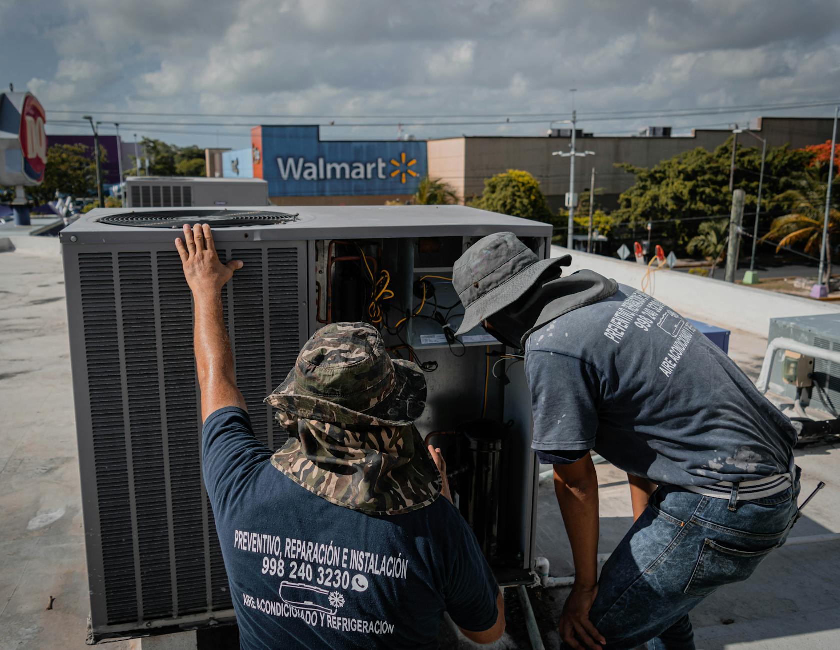 Two technicians repair a rooftop HVAC unit outside a Walmart store. - healthy snacks walmart