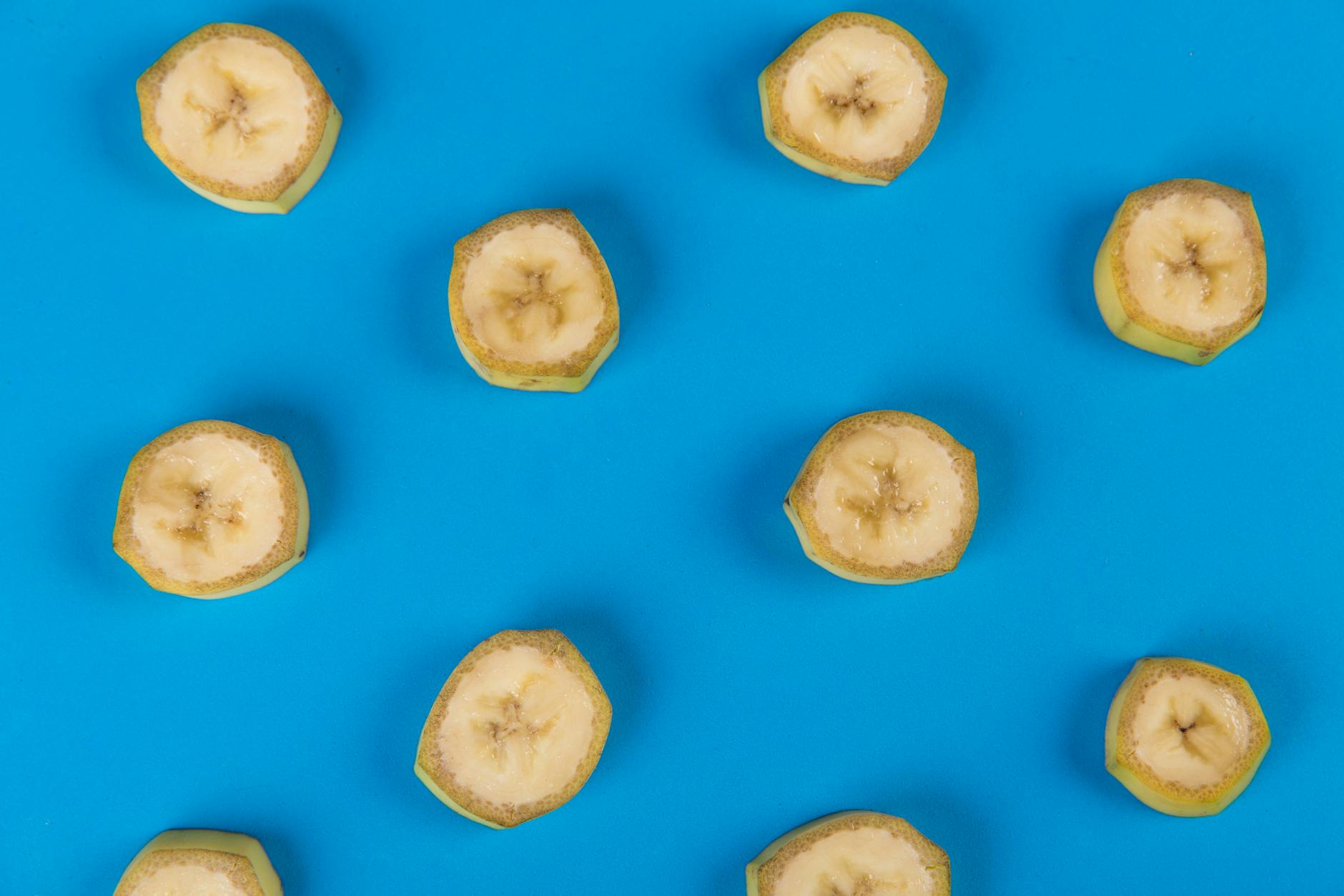 A top-down view of sliced bananas arranged on a vibrant blue background, showcasing a tropical fruit pattern. - healthy snacks walmart