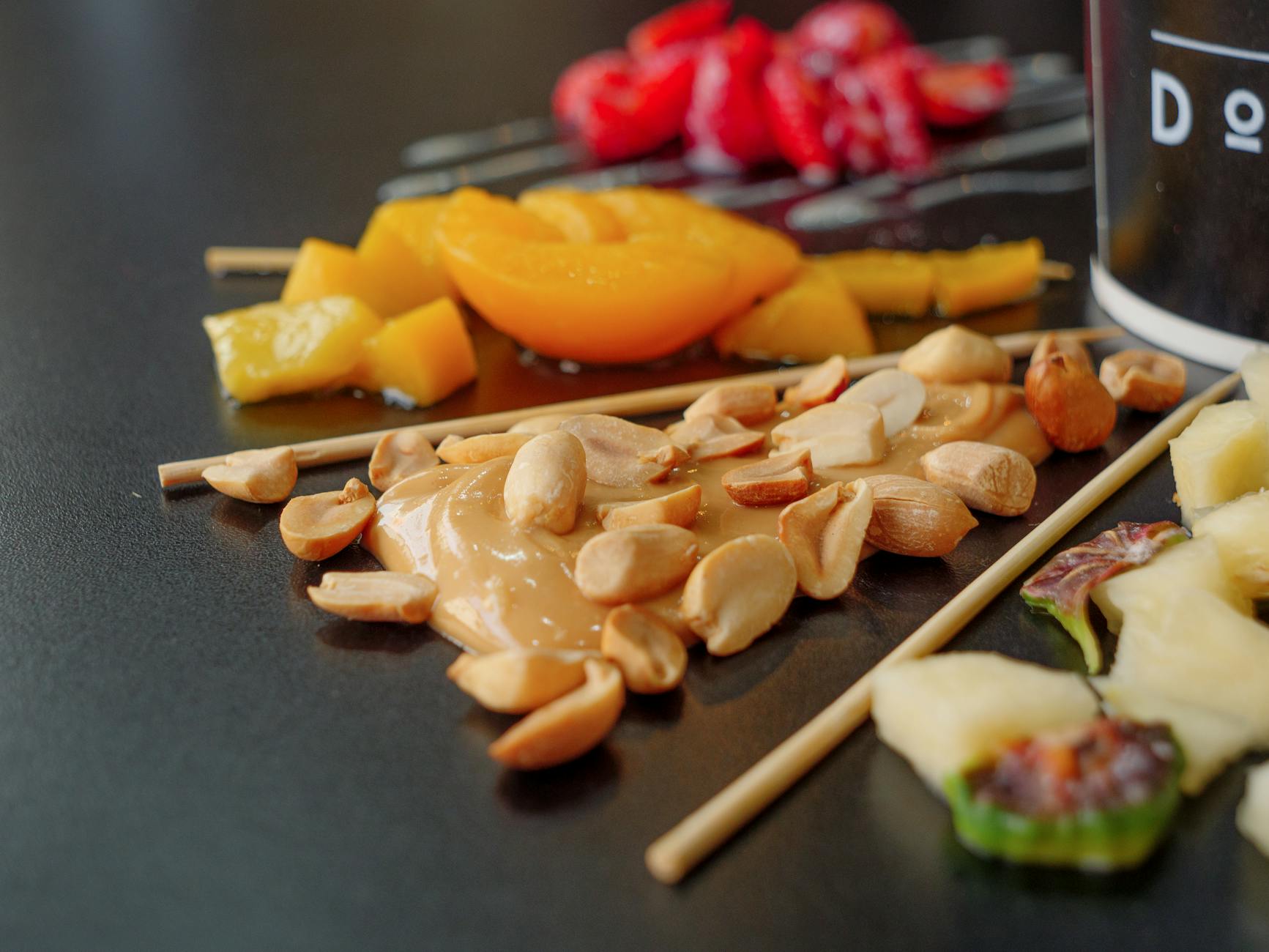Close-up of assorted fruits, nuts, and peanut butter on skewers, showcasing a vibrant, healthy snack. - healthy sweet snacks