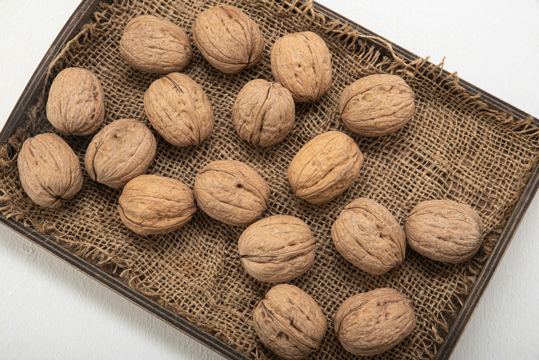 High-angle shot of whole walnuts on a burlap-lined tray, showcasing natural textures. - high fiber foods