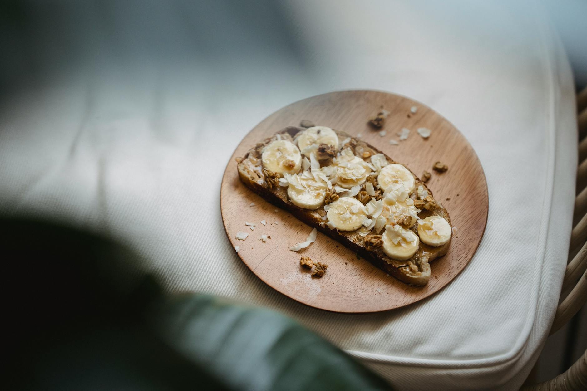 Sliced banana and peanut butter on rye toast presented on a wooden plate, offering a healthy snack. - high fiber foods