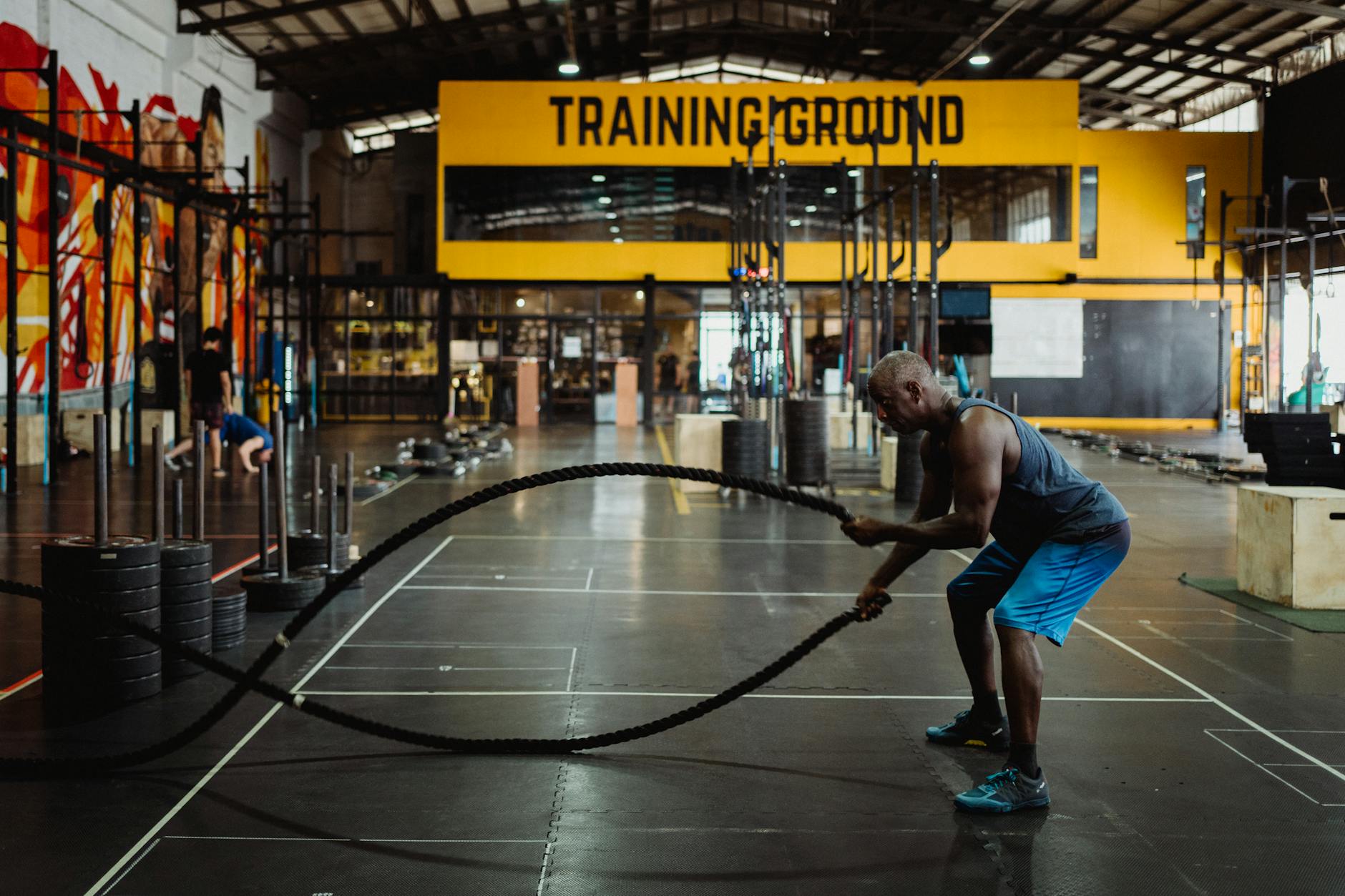 Athletic man engaging in a battle rope workout inside a modern gym setting for fitness training. - hiit cardio workout