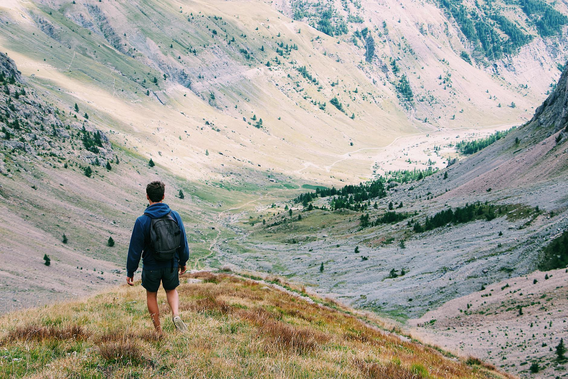 A lone hiker with a backpack explores a scenic mountain valley, surrounded by nature's beauty. - hiking calorie burn
