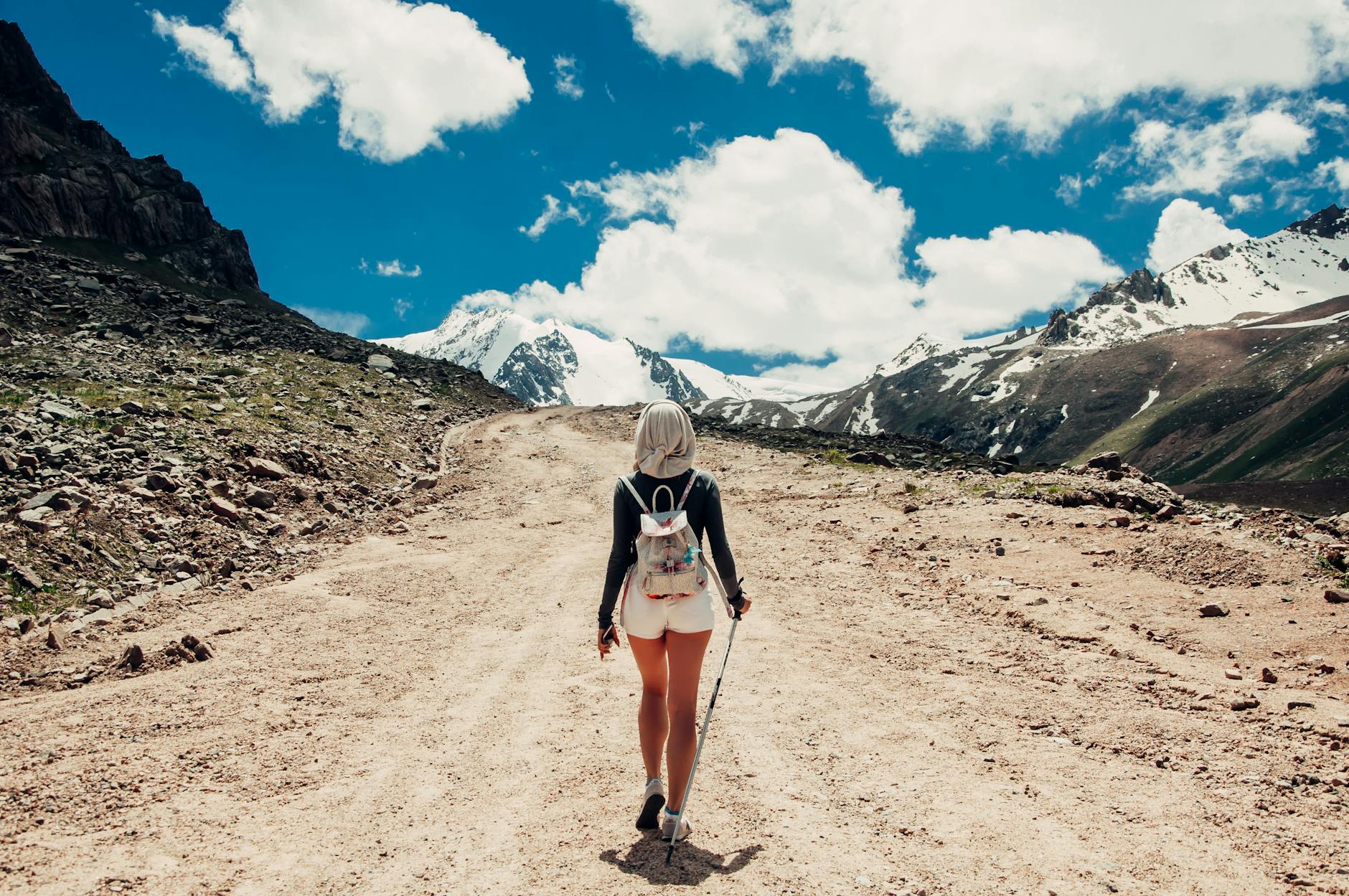 Back view of a woman hiking on a scenic mountain trail during daylight. - hiking for weight loss