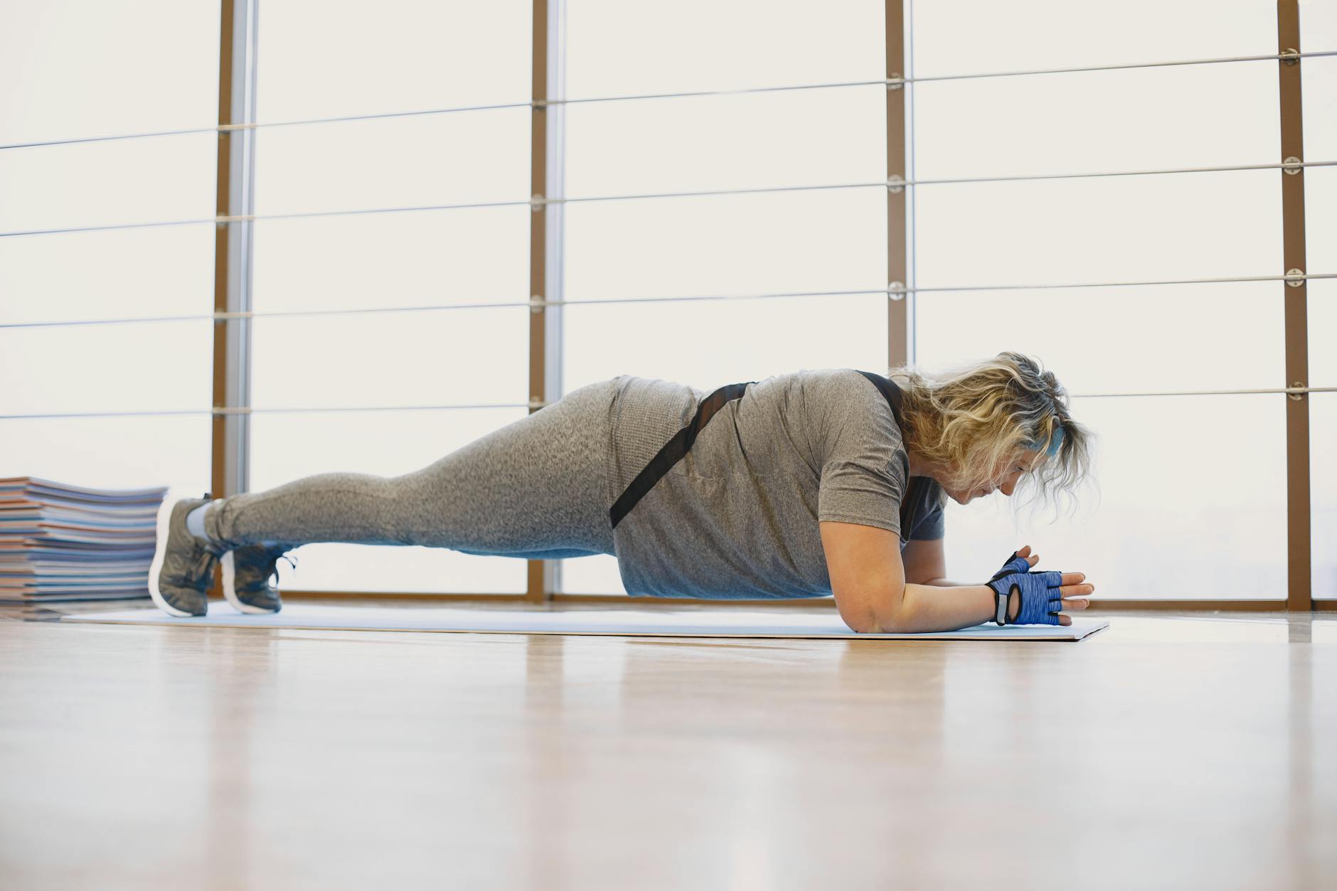 A woman in activewear doing a plank exercise indoors on a yoga mat, promoting fitness and wellness. - home fat burning workout