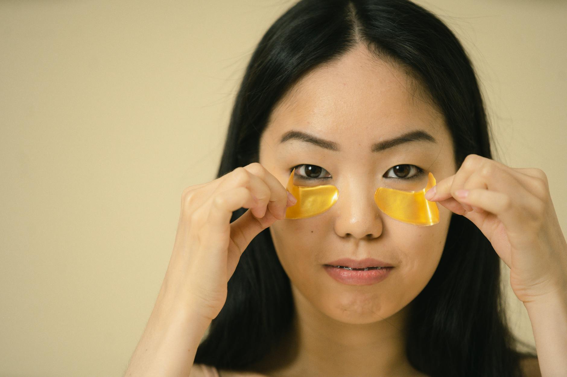 Close-up of a woman applying golden eye patches during her skincare routine, highlighting beauty and self-care. - hydration tips spring