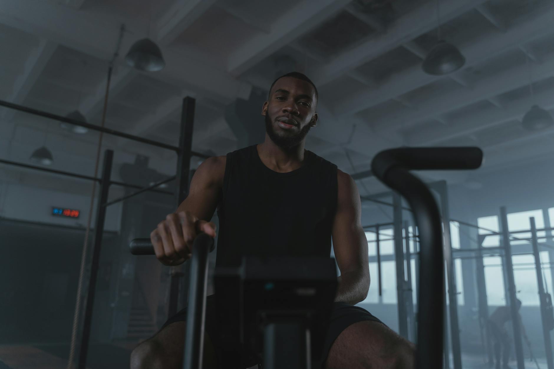 Black man training on exercise bike in modern gym setting, promoting fitness and healthy lifestyle. - interval training workouts