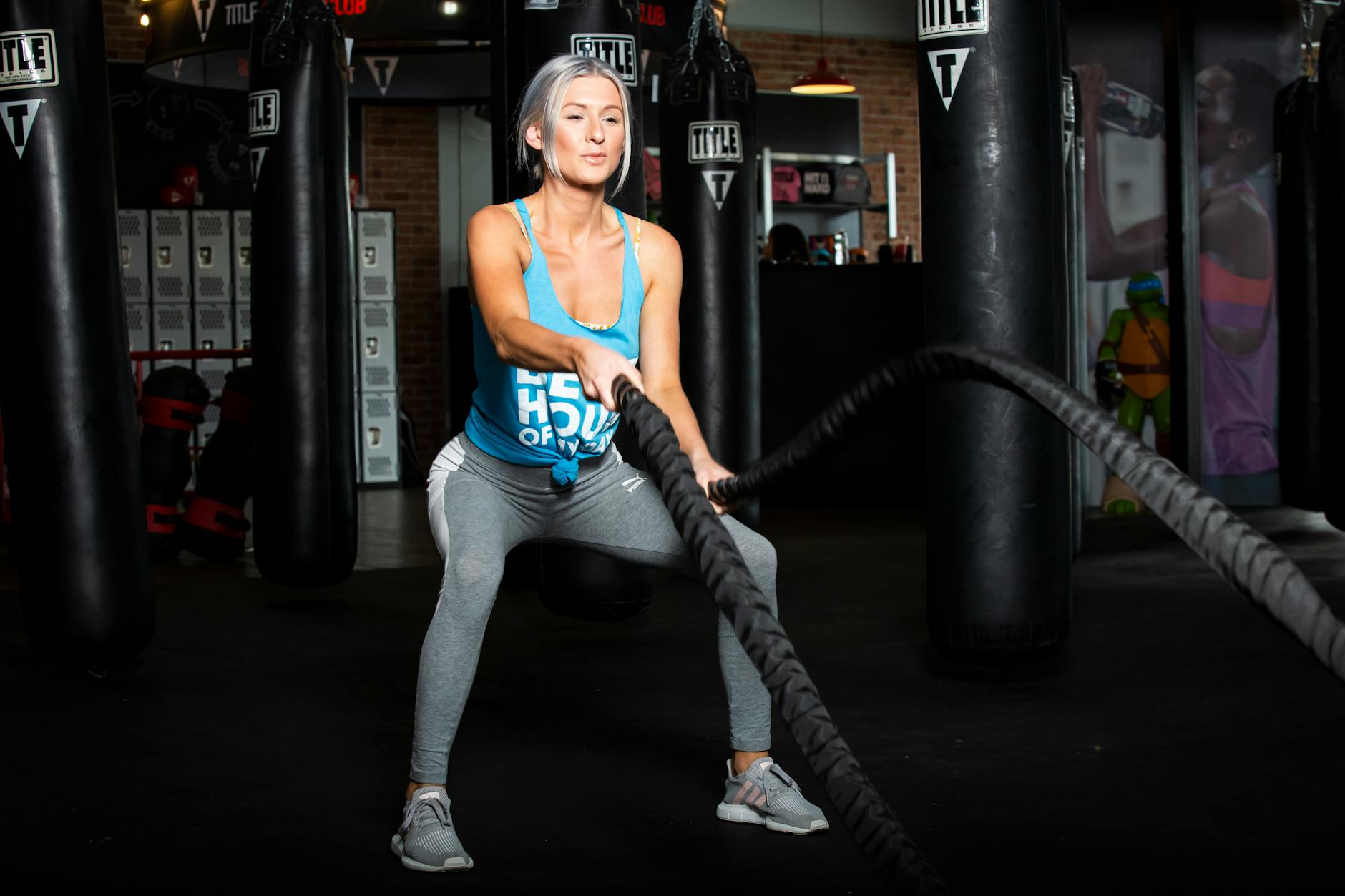 Woman working out with battle ropes in a gym, promoting a healthy lifestyle. - interval training workouts