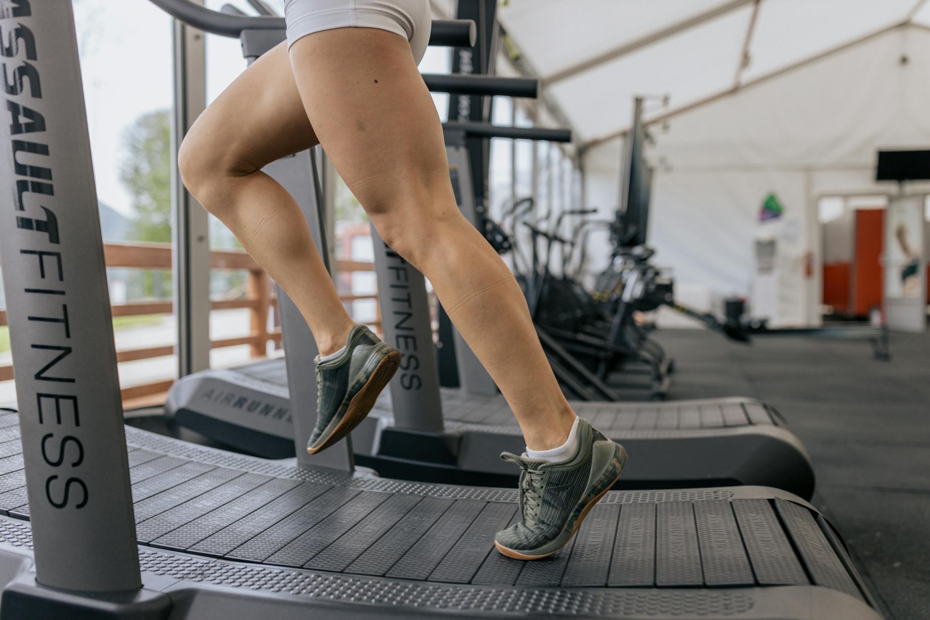 Close-up of a woman's legs running on a treadmill indoors, focusing on fitness and exercise. - leg workout routine