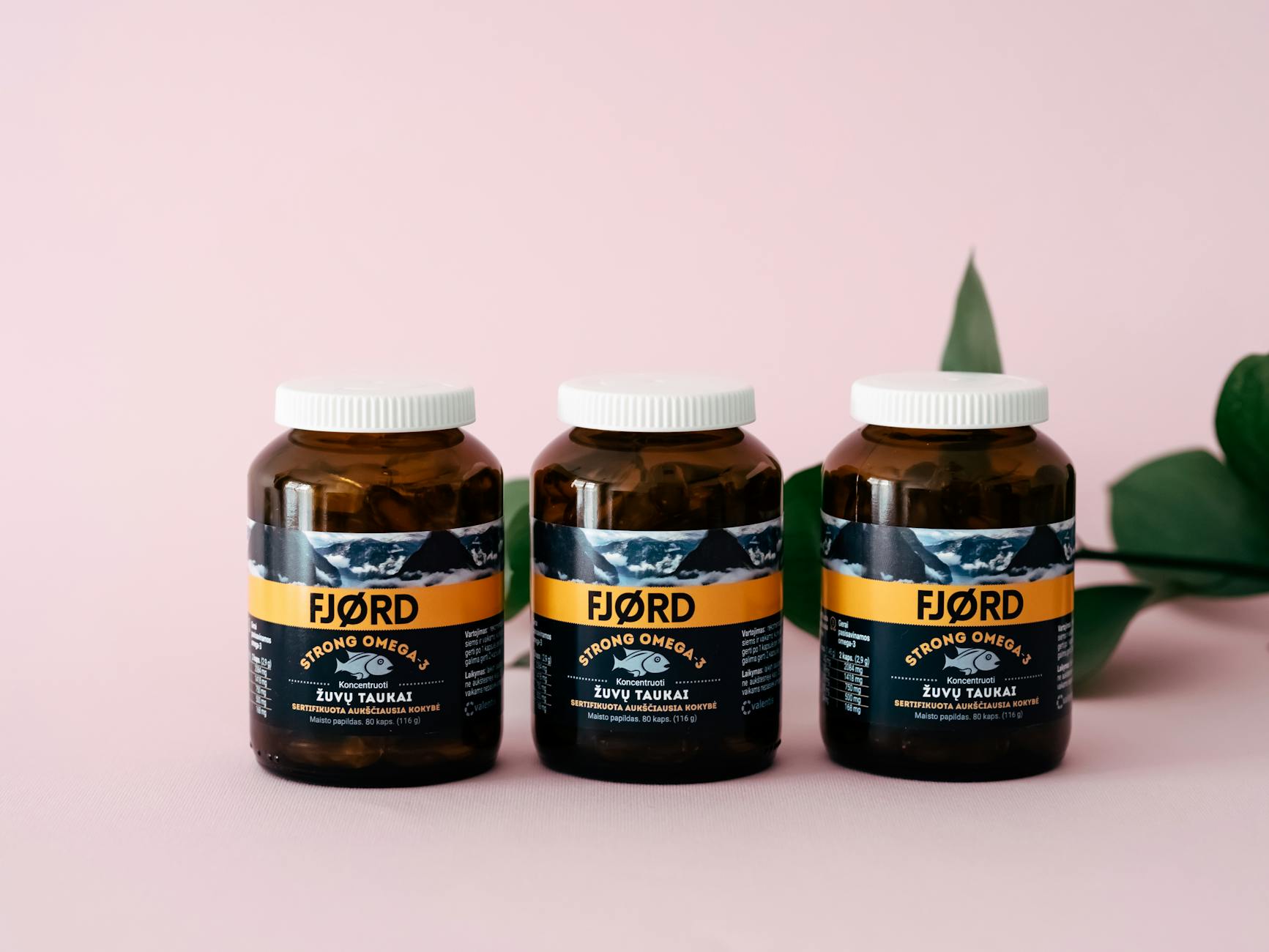 Three FJORD Omega-3 supplement bottles on a pink backdrop with greenery accents. - magnesium oil benefits