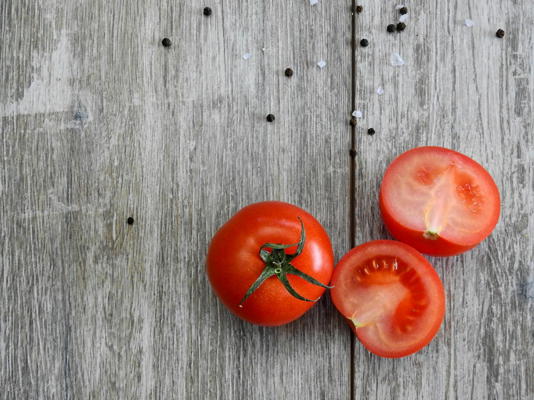 Close-up of ripe tomatoes on a rustic wooden table with peppercorns. - magnesium oxide benefits