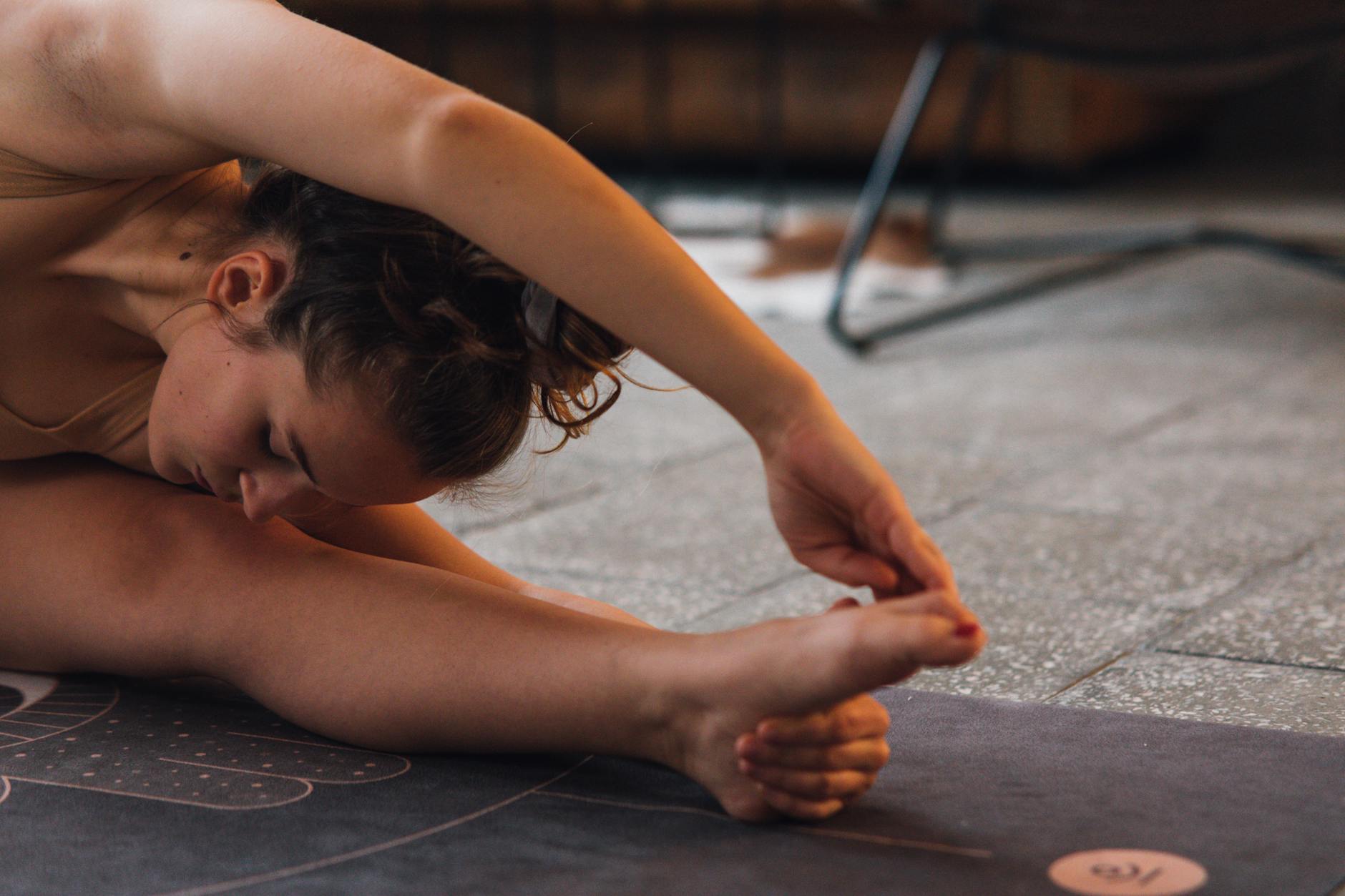 Woman stretching on a yoga mat indoors, showcasing flexibility and focus. - mindfulness exercises