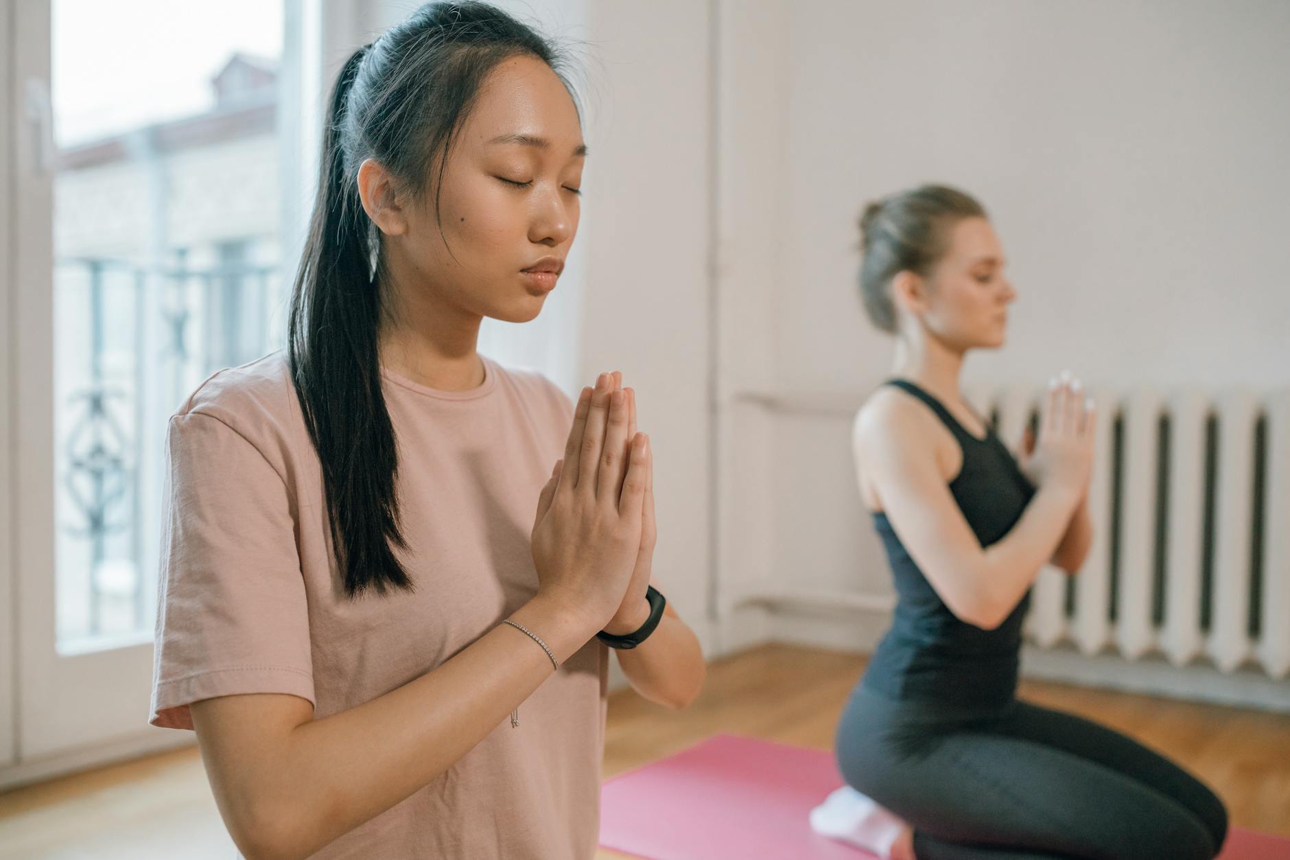 Two women engaging in a serene yoga practice, focusing on meditation for mental wellness. - mindfulness meditation benefits