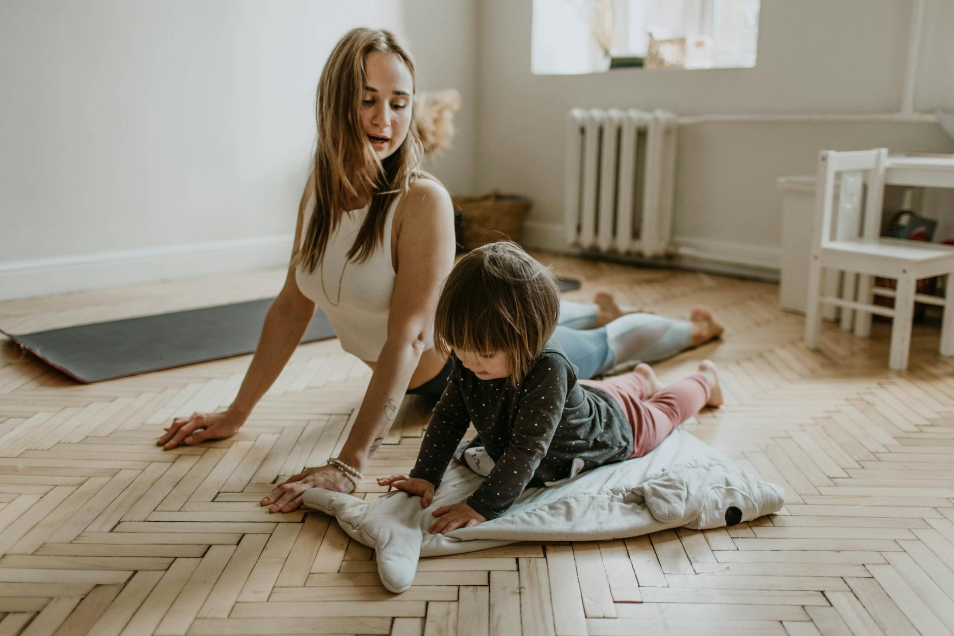 A mother and child practicing yoga together at home on a sunny day, fostering wellness and connection. - morning exercise kids
