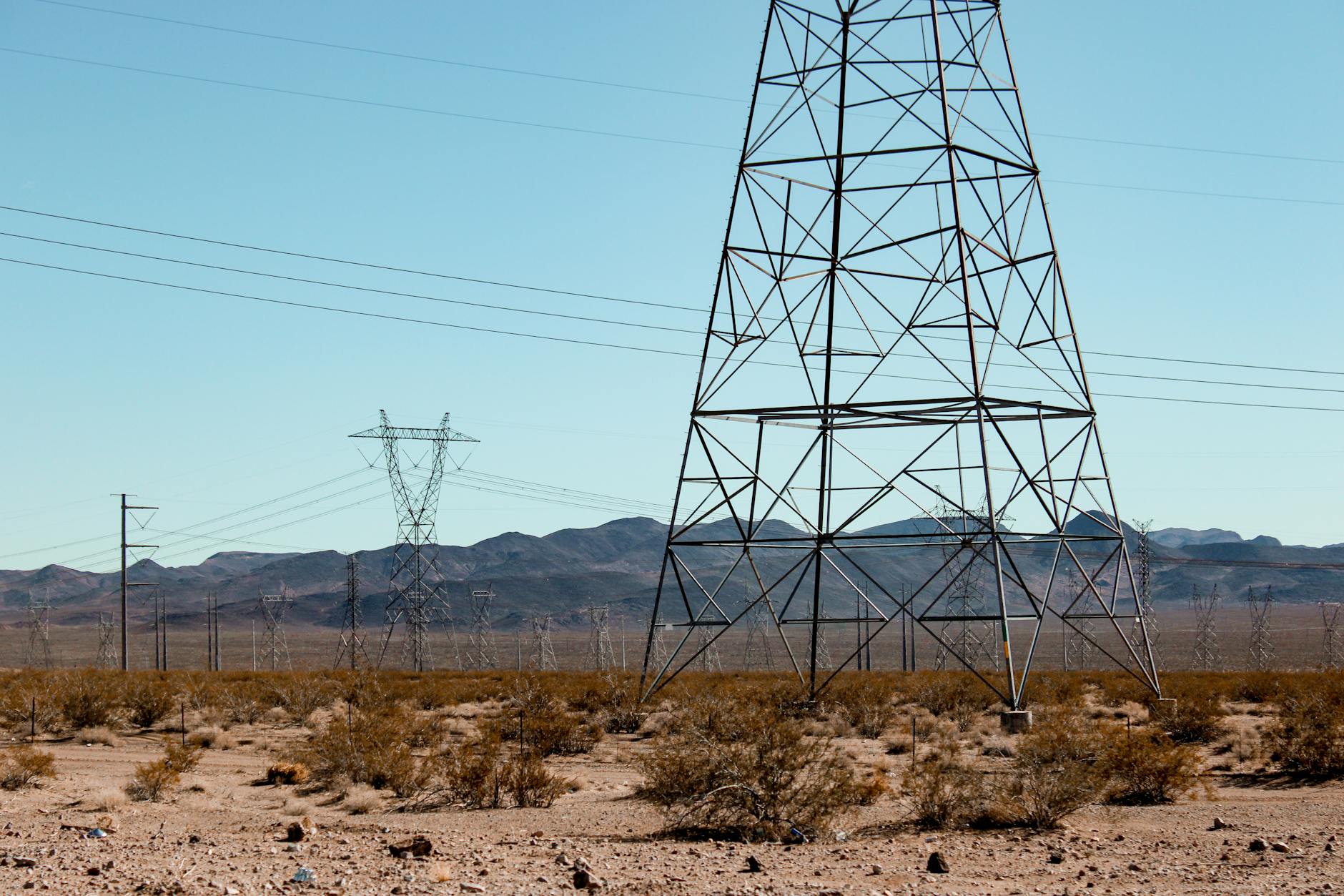 High voltage power lines stand tall in the vast Nevada desert under a clear blue sky. - natural energy boosters