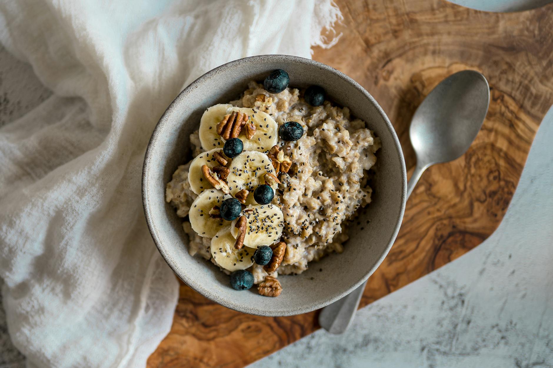 A nutritious bowl of oatmeal topped with bananas, blueberries, pecans, and chia seeds. Perfect healthy breakfast option. - oatmeal benefits