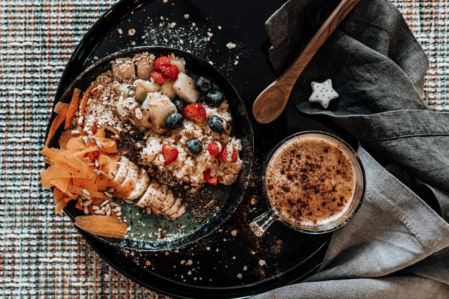 A delicious top view of a fruit and nut breakfast bowl with a fresh cup of coffee on a stylish table setting. - oatmeal benefits