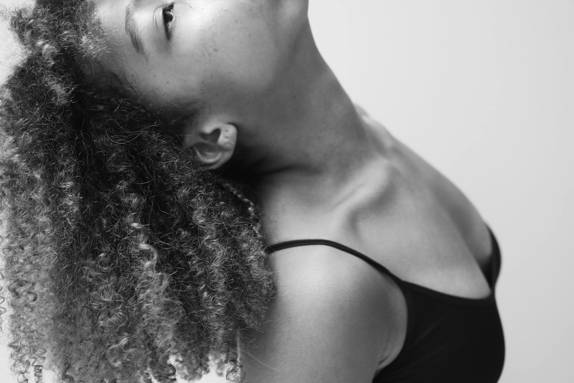 Artistic black and white portrait of a woman looking upwards with curly hair. - posture corrector