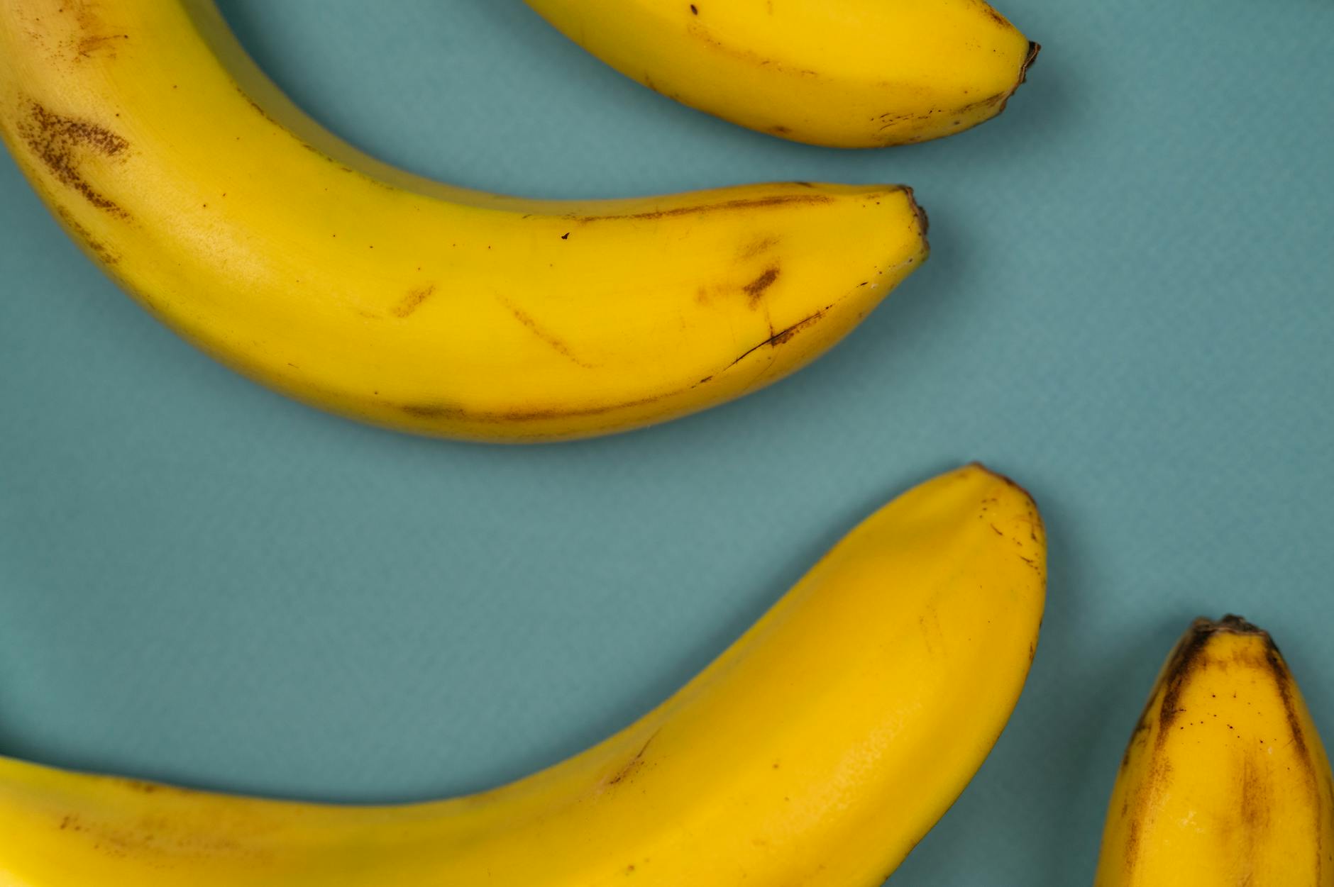 From above of tasty ripe bananas with blots on smooth yellow peel on blue background - potassium rich foods