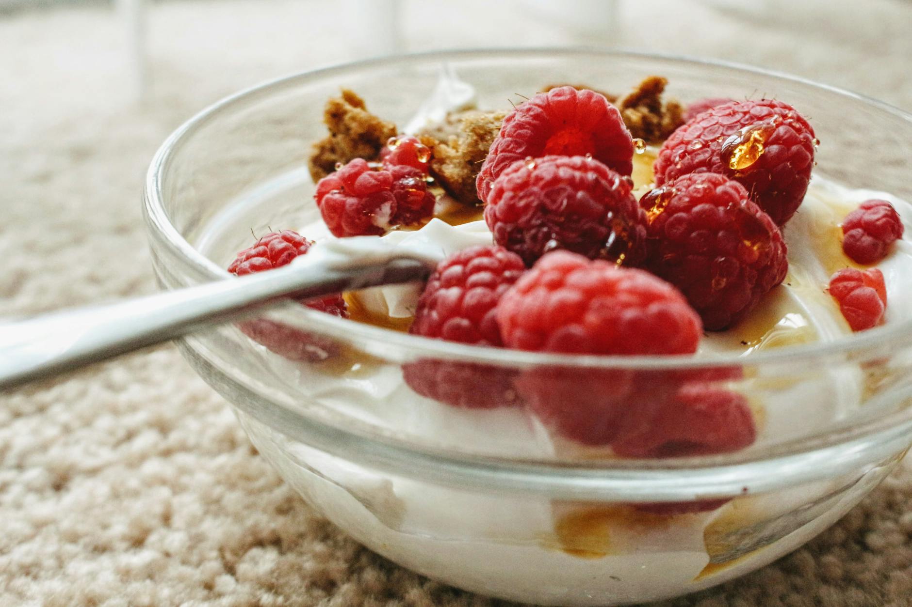 Indulge in creamy yogurt topped with fresh raspberries and sweet honey in a glass bowl. - probiotics benefits