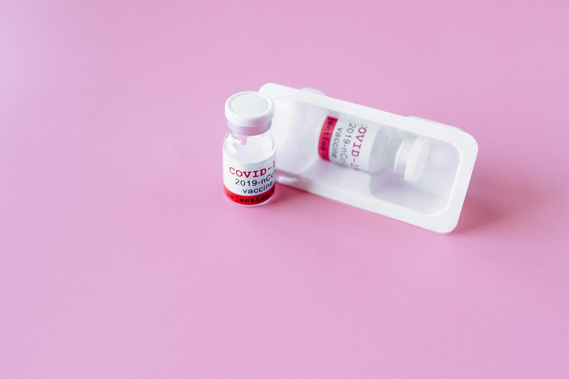 Close-up of COVID-19 vaccine vials on a pink surface, symbolizing healthcare and immunization. - probiotics spring immunity