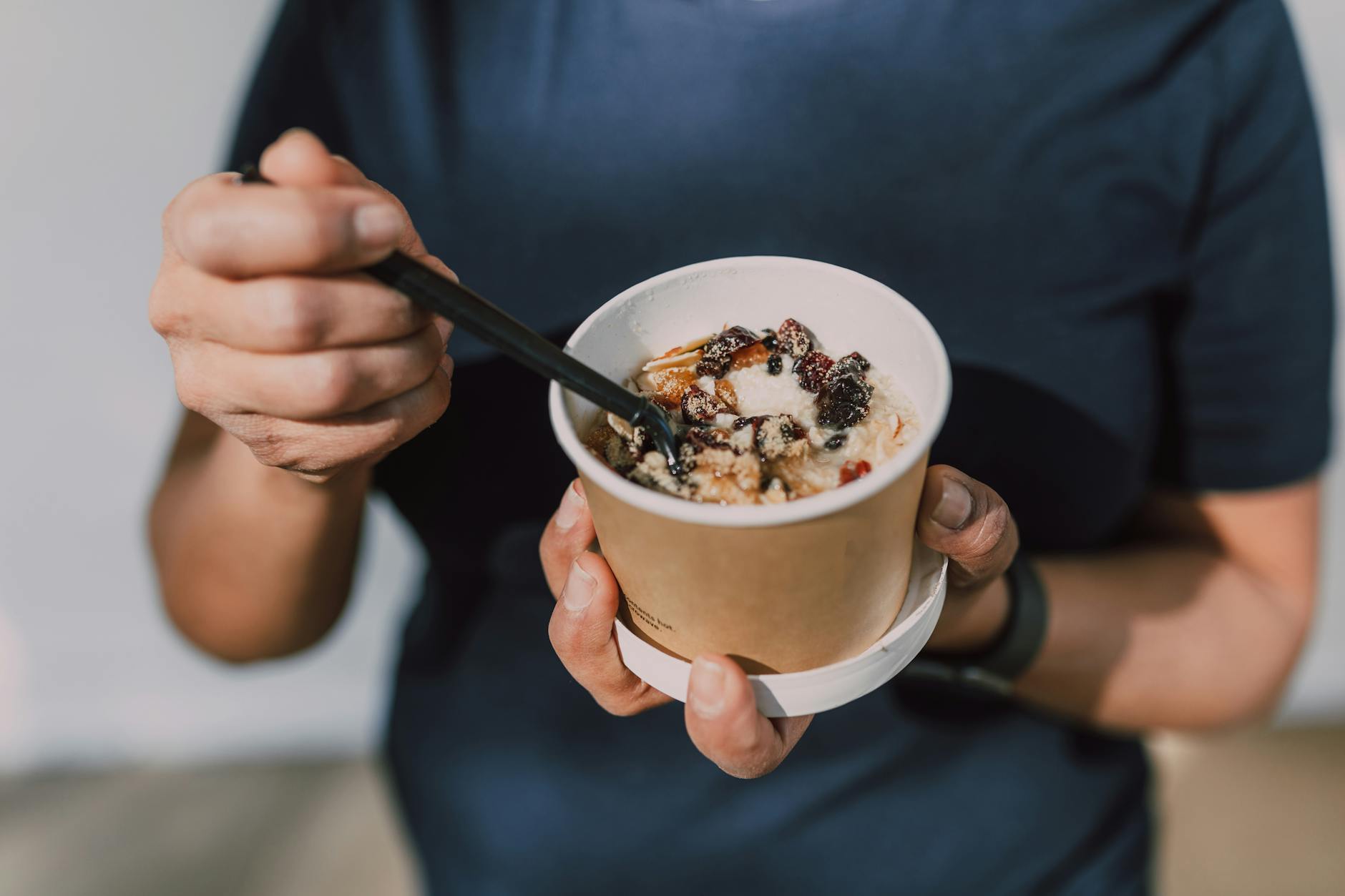 Hands holding a cup of vegan oatmeal with fruits and nuts, perfect for a healthy breakfast on the go. - quick healthy breakfast