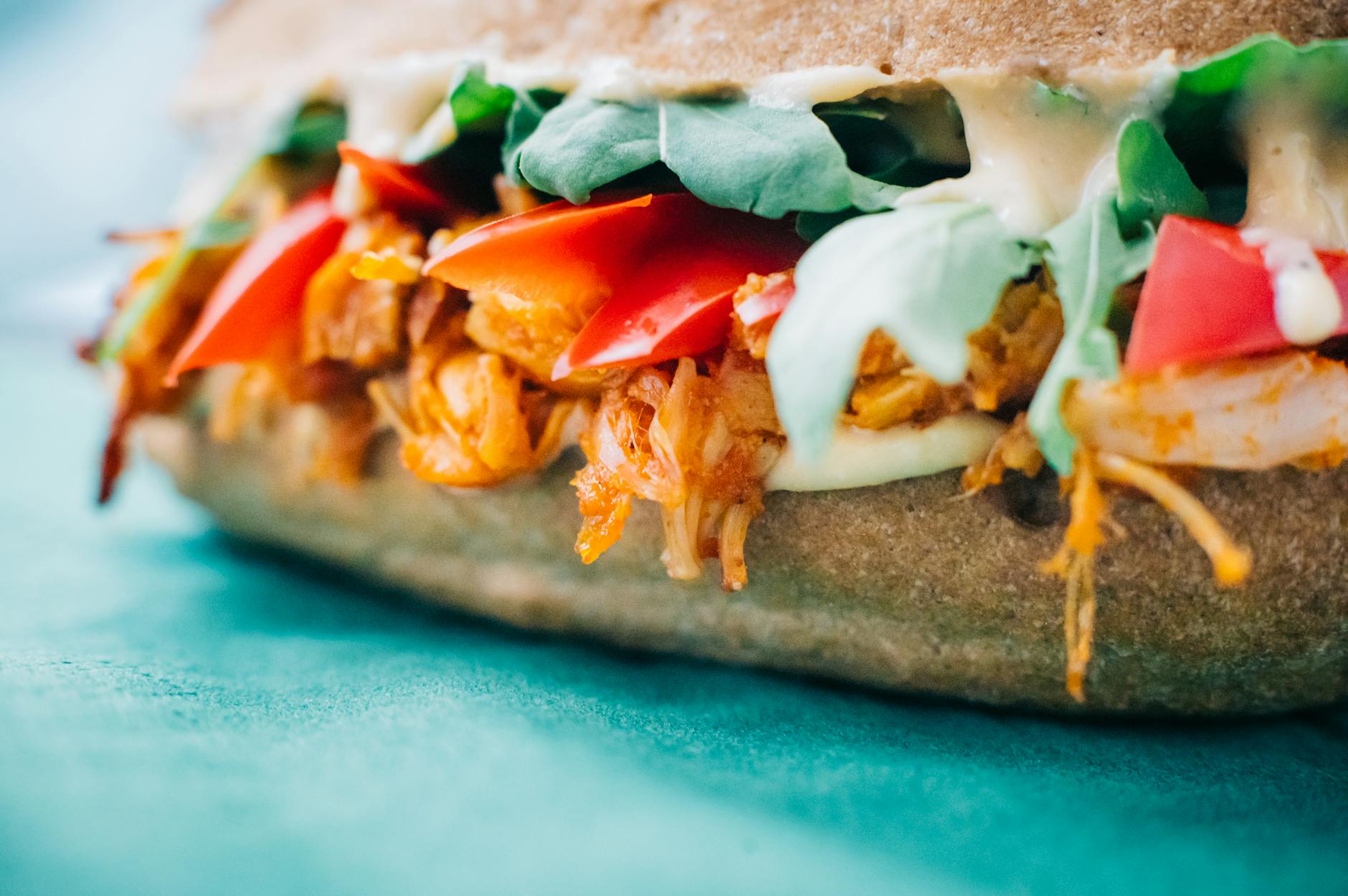 Mouthwatering chicken sandwich with fresh veggies and sauce on colorful background. - quick healthy dinners