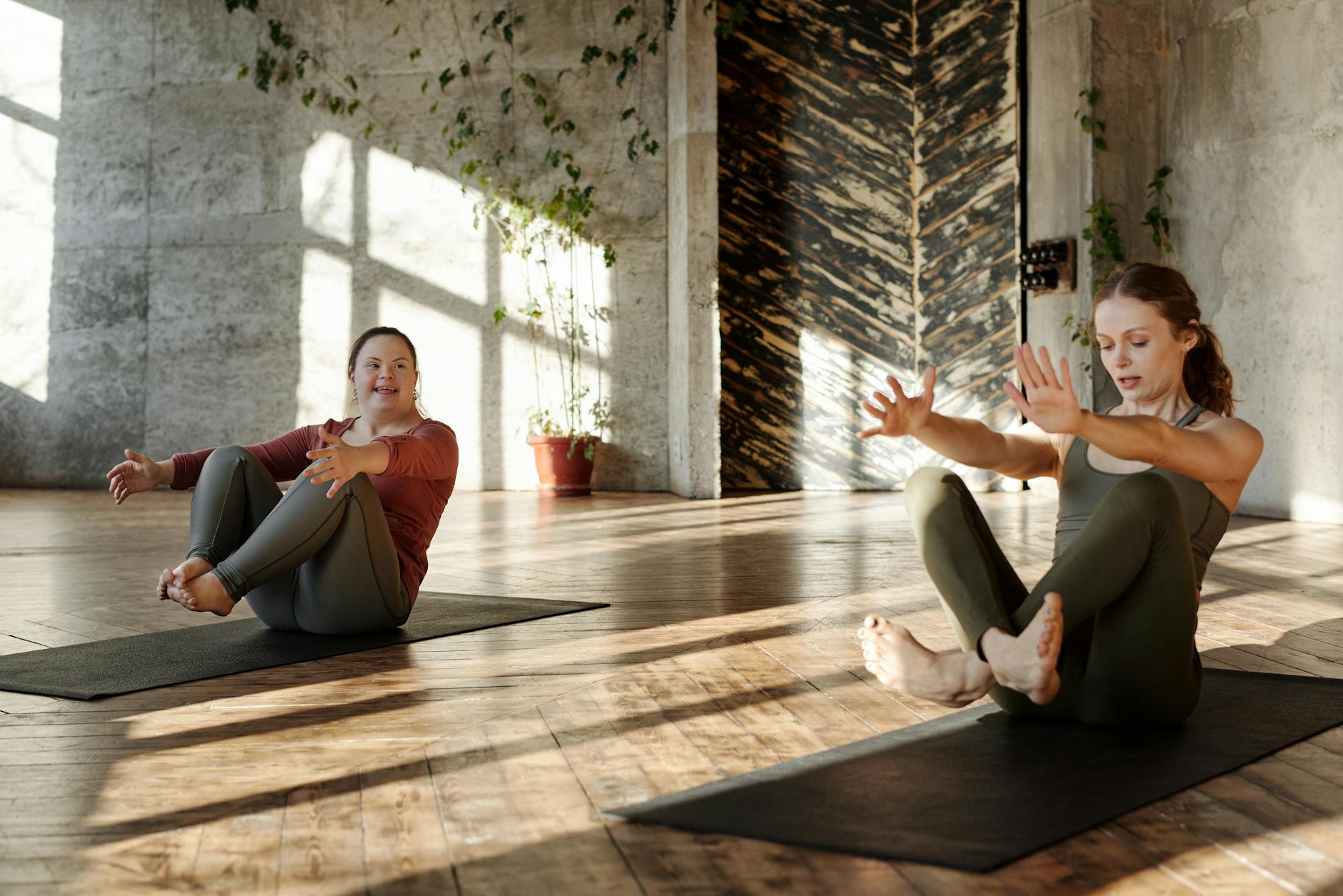 Two women practicing yoga indoors, promoting flexibility and wellness. - quick morning yoga