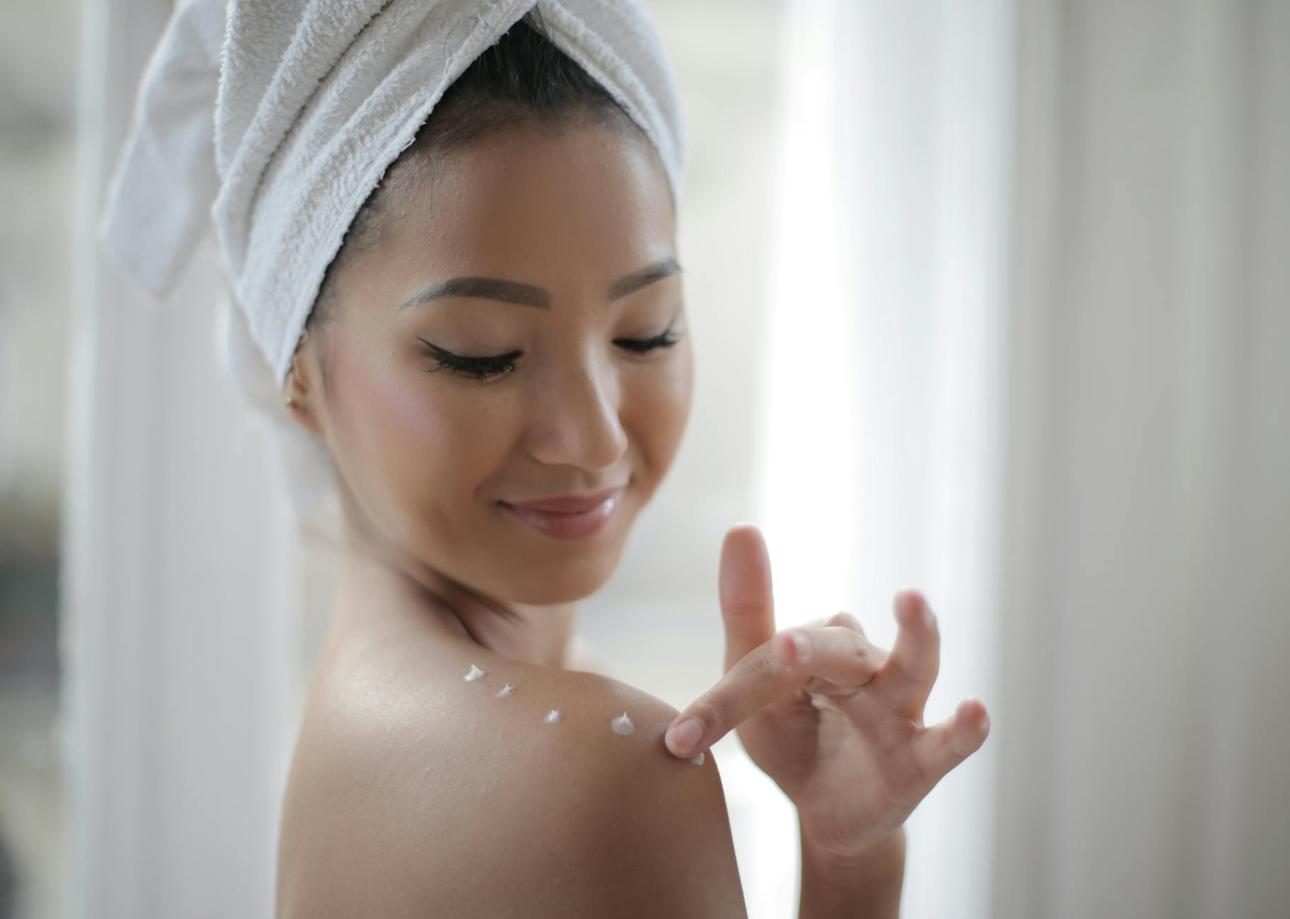 Elegant portrait of a woman applying skincare cream indoors, highlighting beauty and relaxation. - radiant skin foods