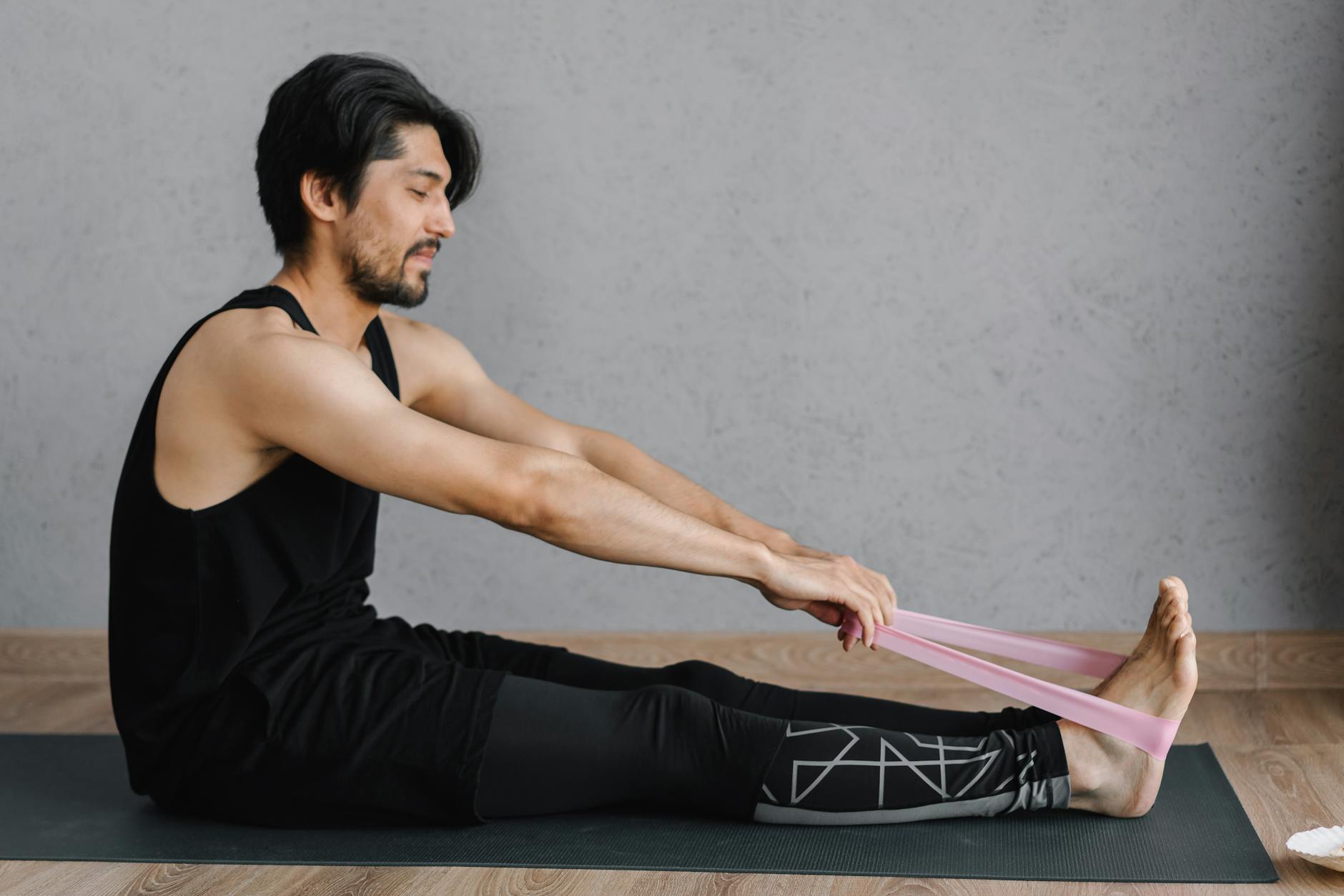 Adult man performing stretching exercises with a resistance band on a yoga mat indoors for fitness and wellness. - resistance band upper body