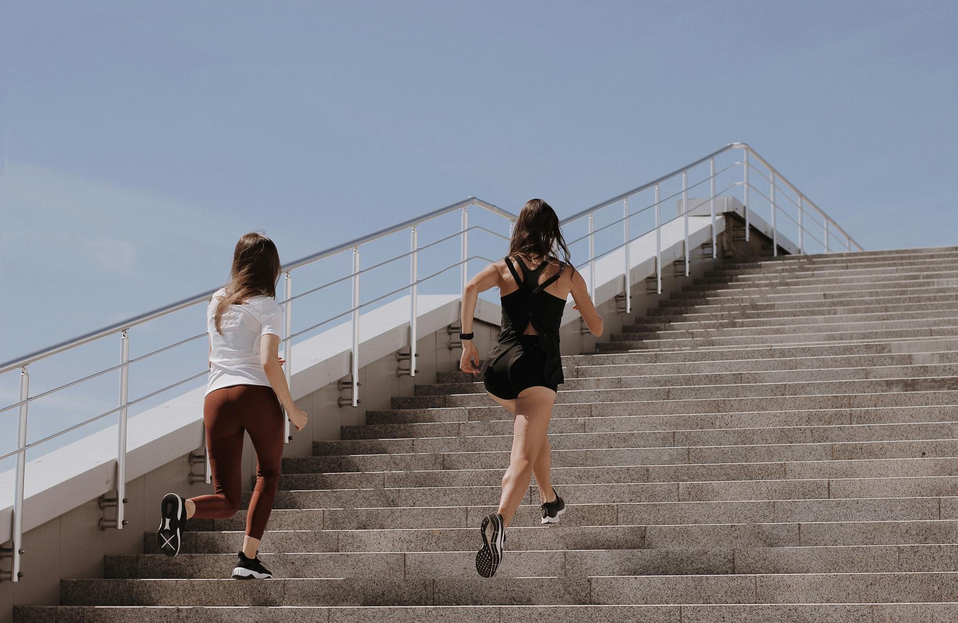 Two women running up stairs outdoors, embodying fitness and wellness. - running for women