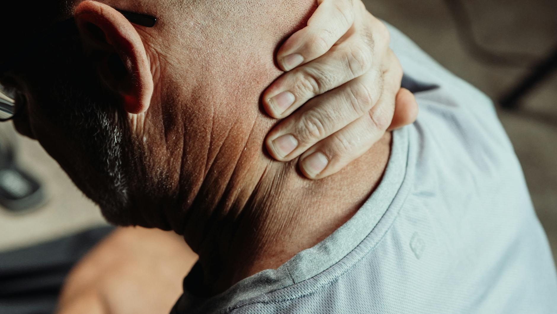 Man with neck pain holding his neck in discomfort, conveying tension or stress. - sciatica pain relief