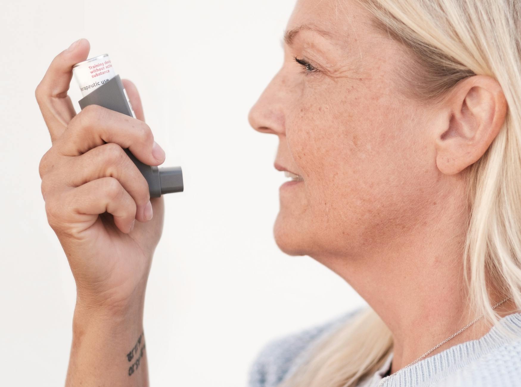 Middle-aged woman using an asthma inhaler to alleviate breathing difficulties. - spring allergy relief