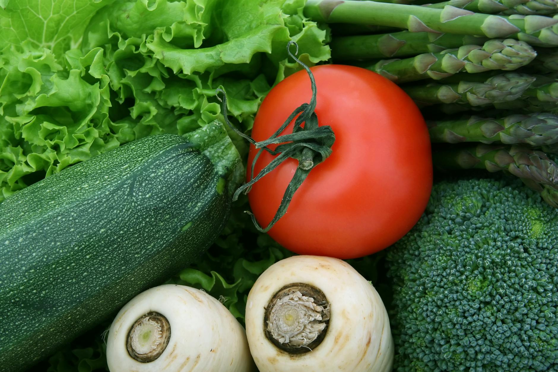 A vibrant close-up of fresh vegetables, including tomato, zucchini, and broccoli, perfect for healthy eating imagery. - spring produce benefits