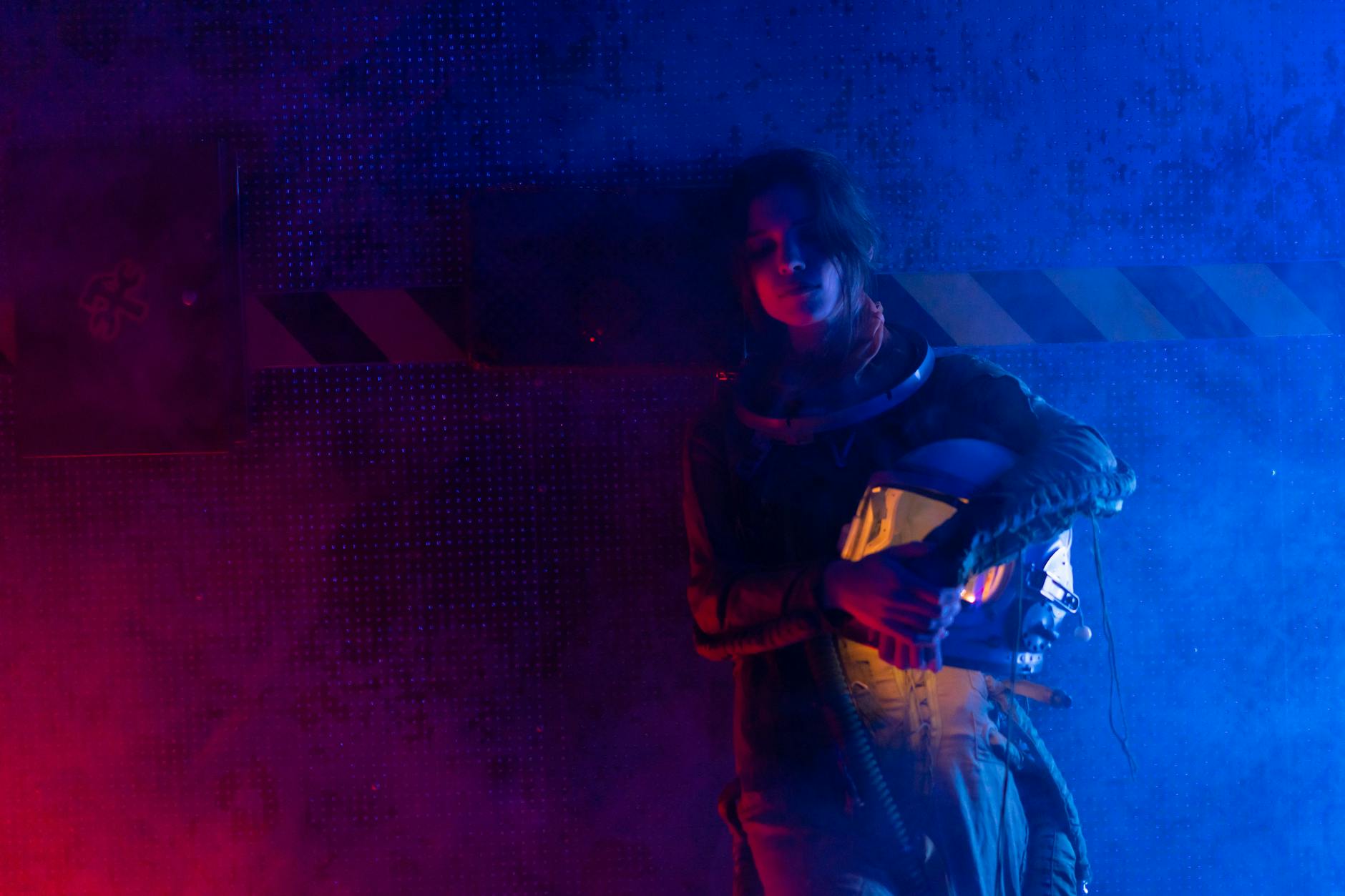 A woman in a space suit stands in dramatic colored lighting, evoking a sci-fi atmosphere. - spring sad science
