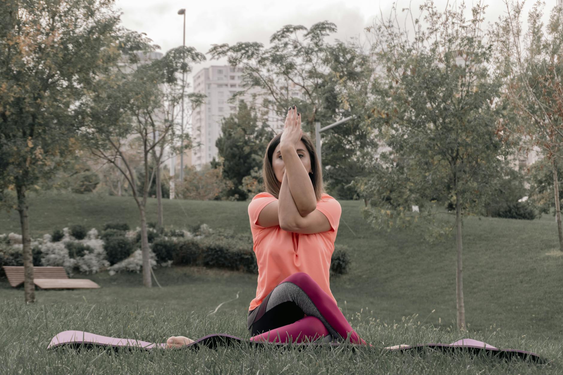 Adult woman performing yoga outdoors in a park. Tranquil setting with greenery and cityscape backdrop. - spring yoga poses
