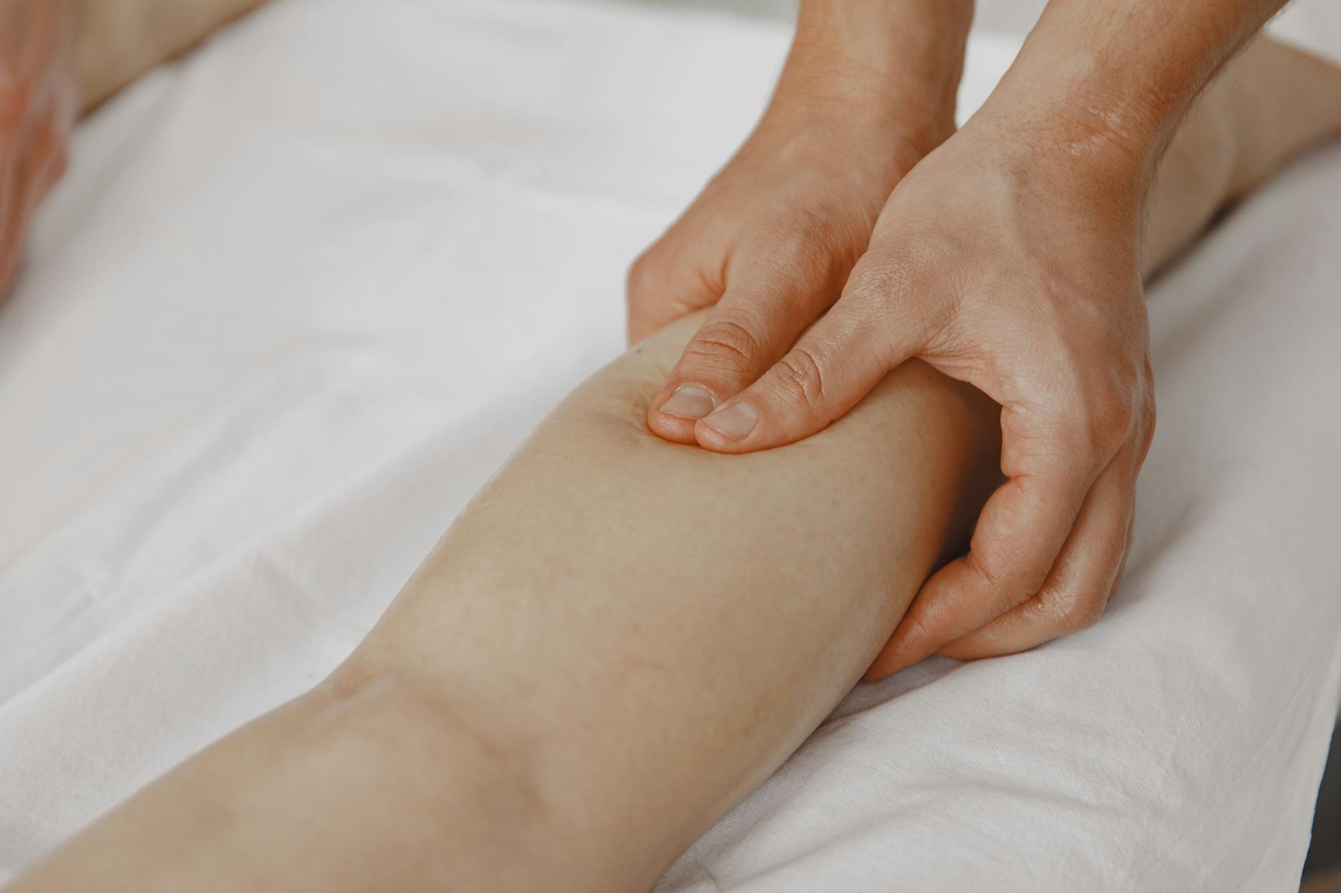 Close-up image of a massage therapist applying pressure on a client's leg for muscle relaxation. - stress relief techniques