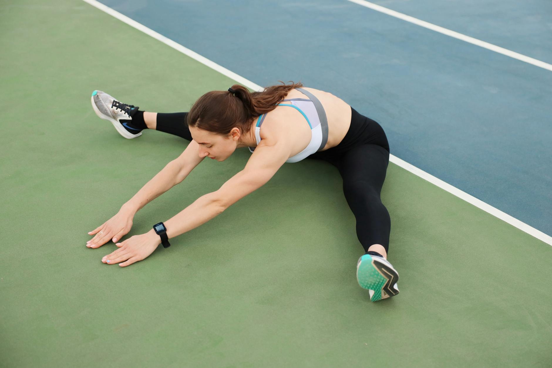 Woman in activewear stretching on a sports court, preparing for a workout. - stretching routine men