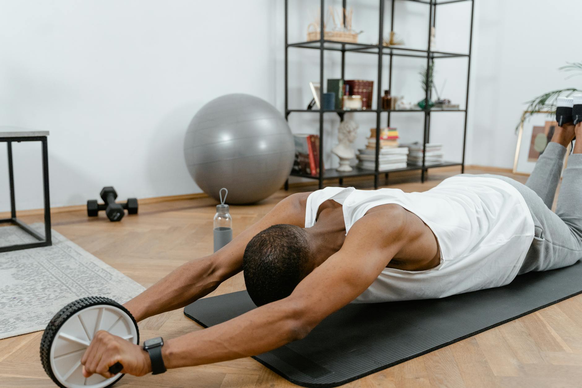 A man performs an ab roller workout indoors, emphasizing healthy lifestyle and fitness. - stretching routine men