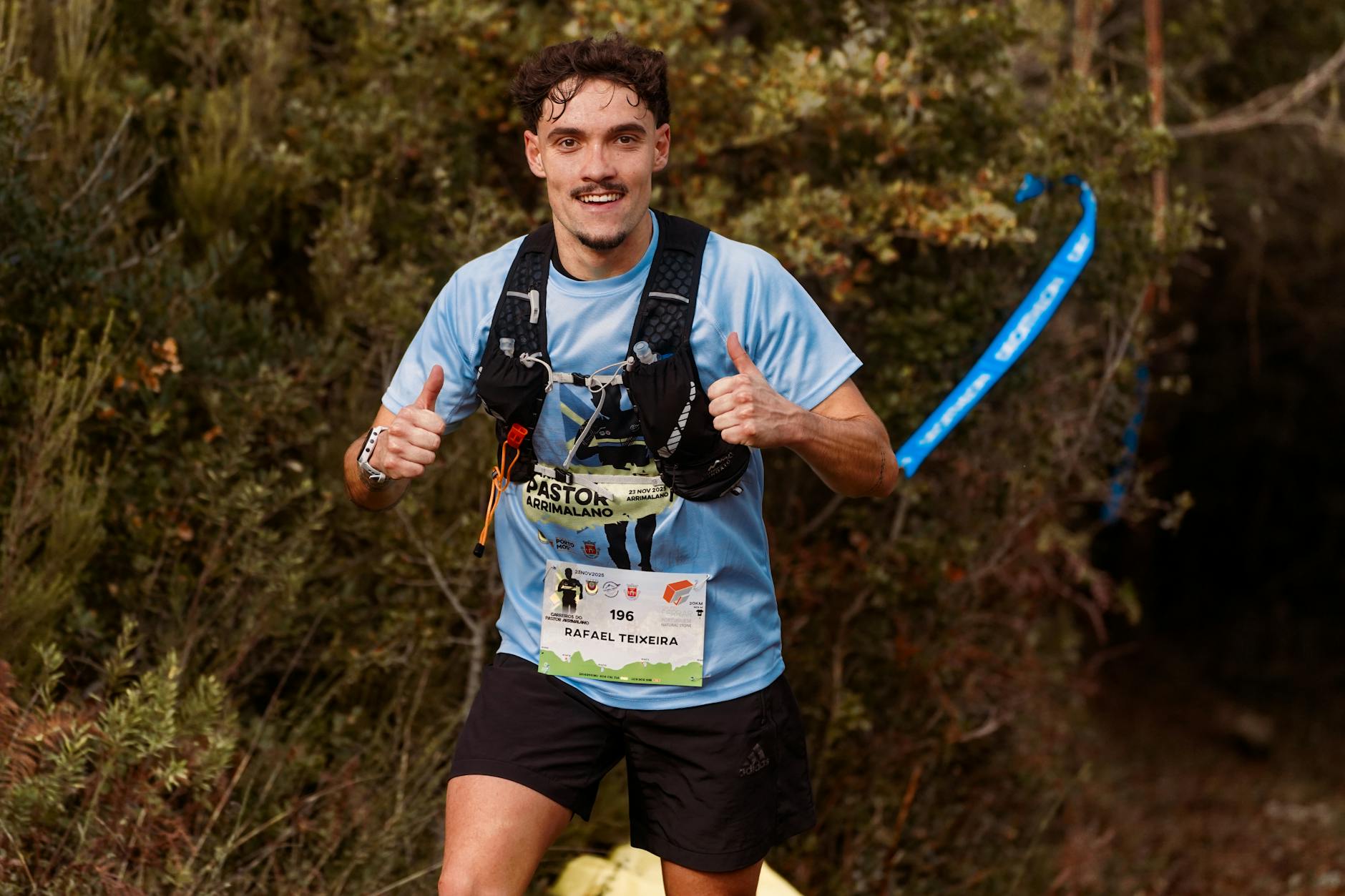 Young male trail runner enthusiastically giving a thumbs up during an outdoor race through forest. - trail running beginners